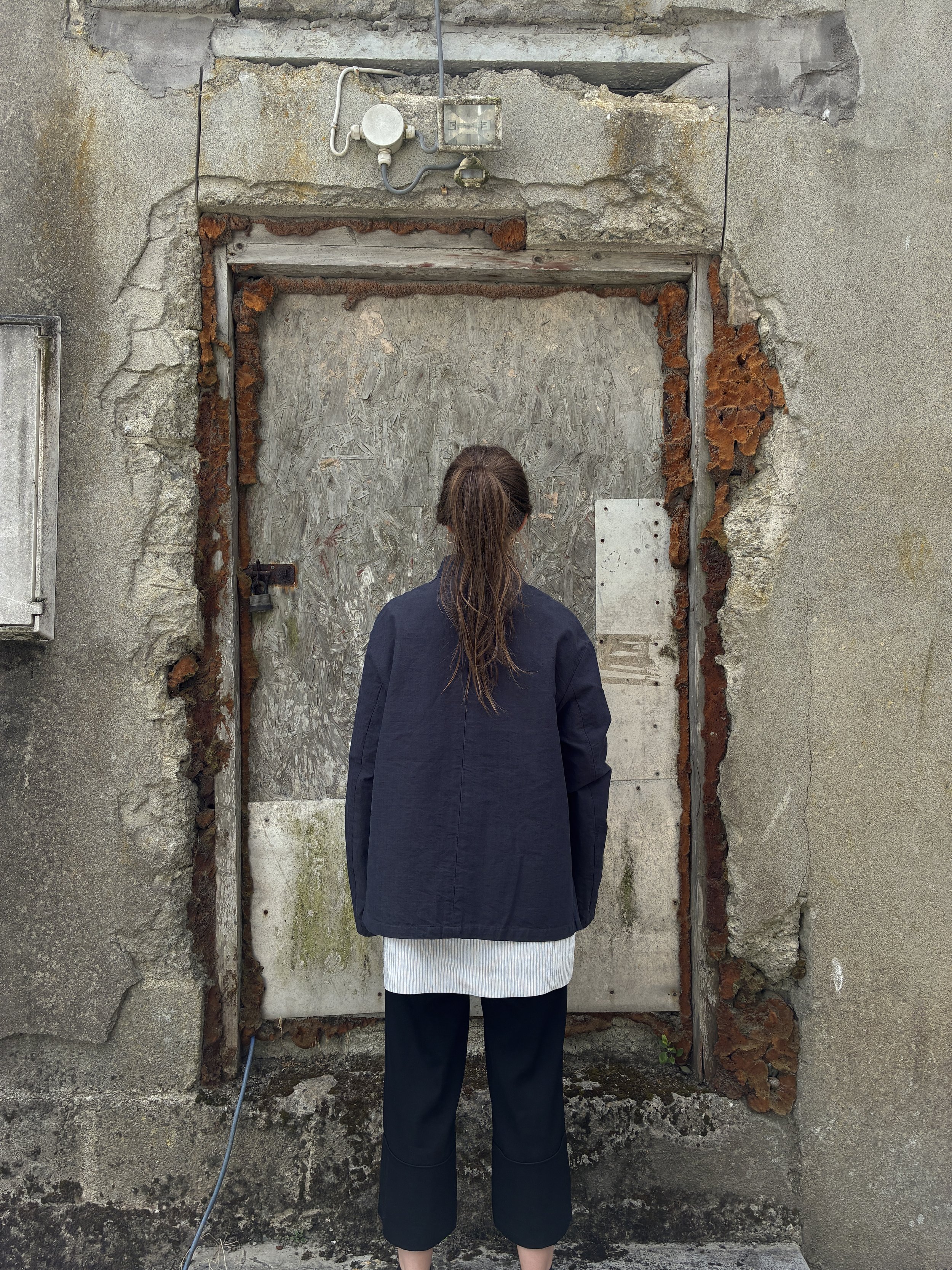 Back of Woman in front of wall wearing Navy 1st PAT-RN Woman Rei Jacket