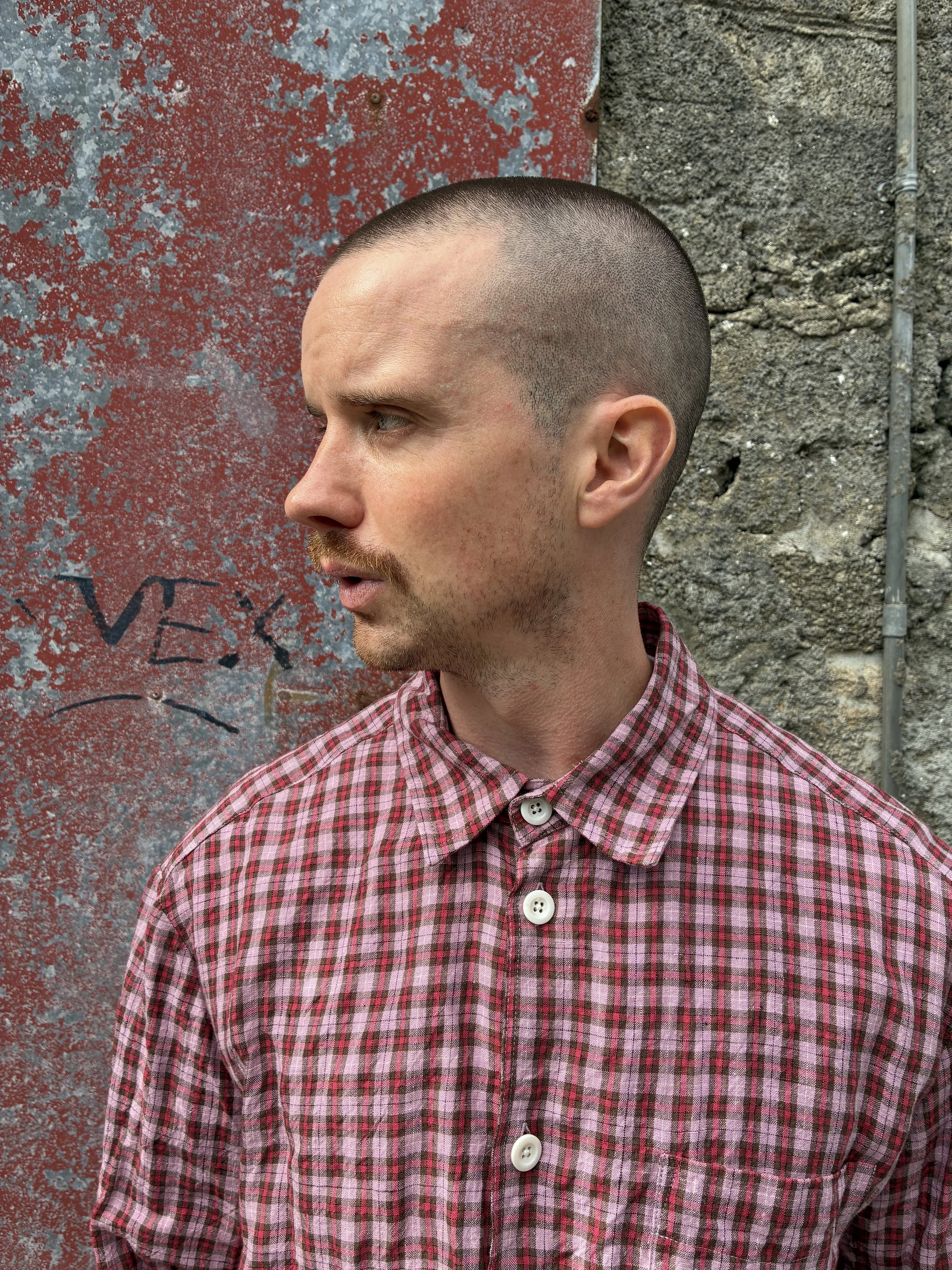 Closeup of Man wearing Conkers Sunrise Relaxed Farmer Shirt in front of red wall