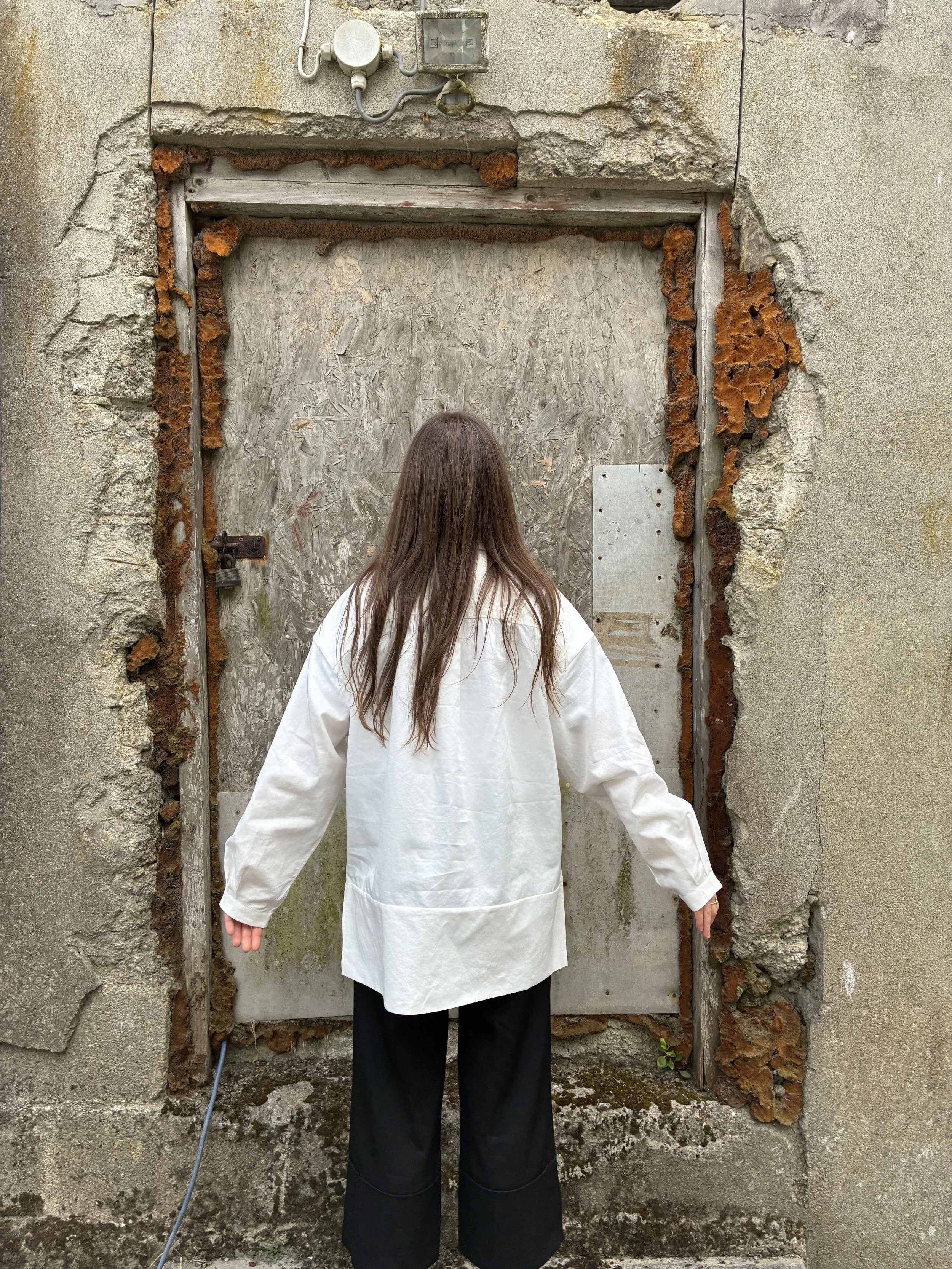 Back of Woman in front of wall wearing White 1st PAT-RN Woman Modula Shirt