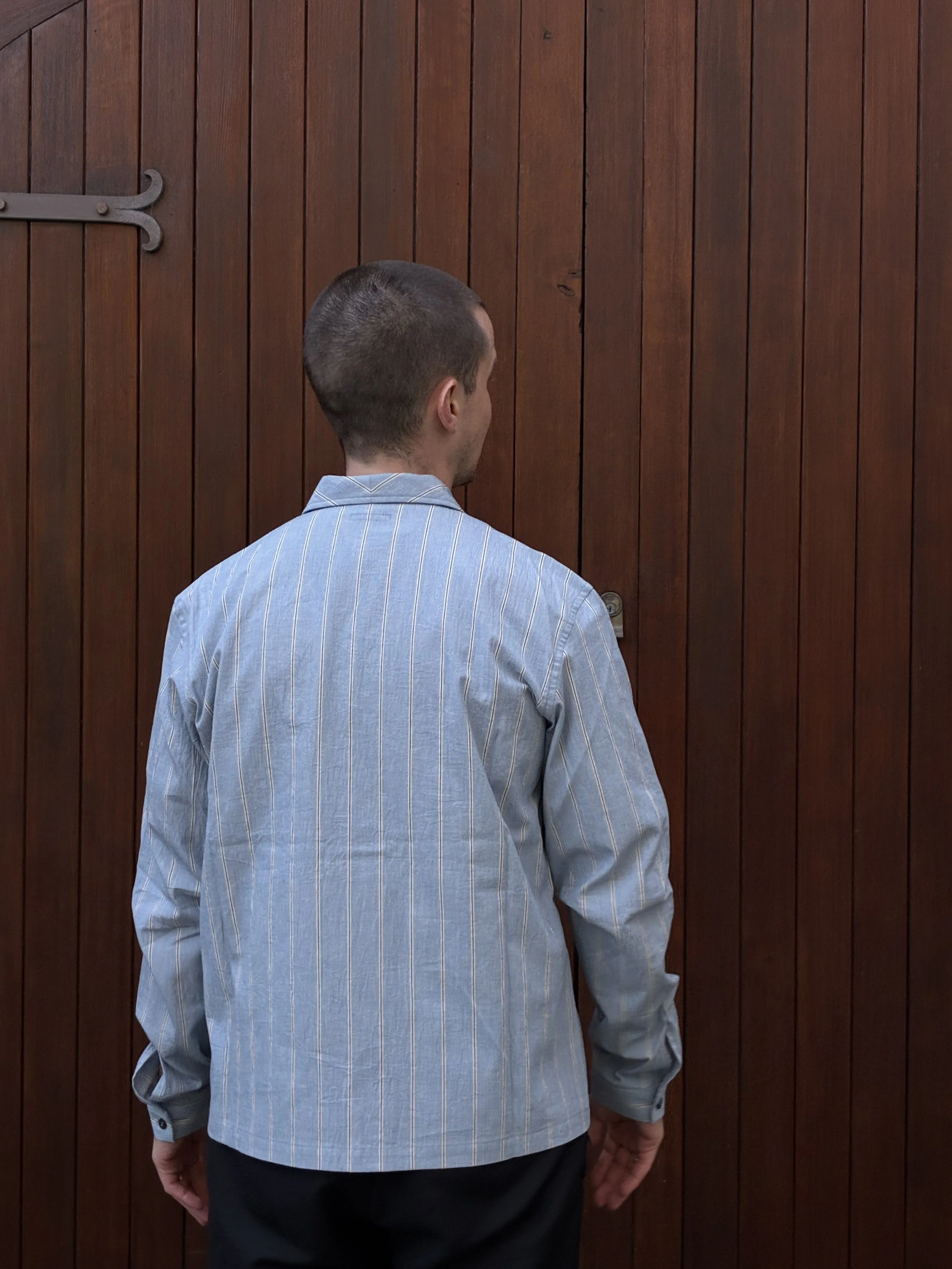 Back of man wearing Frank Leder Japanese Cotton Blue Striped Shirt in front of door