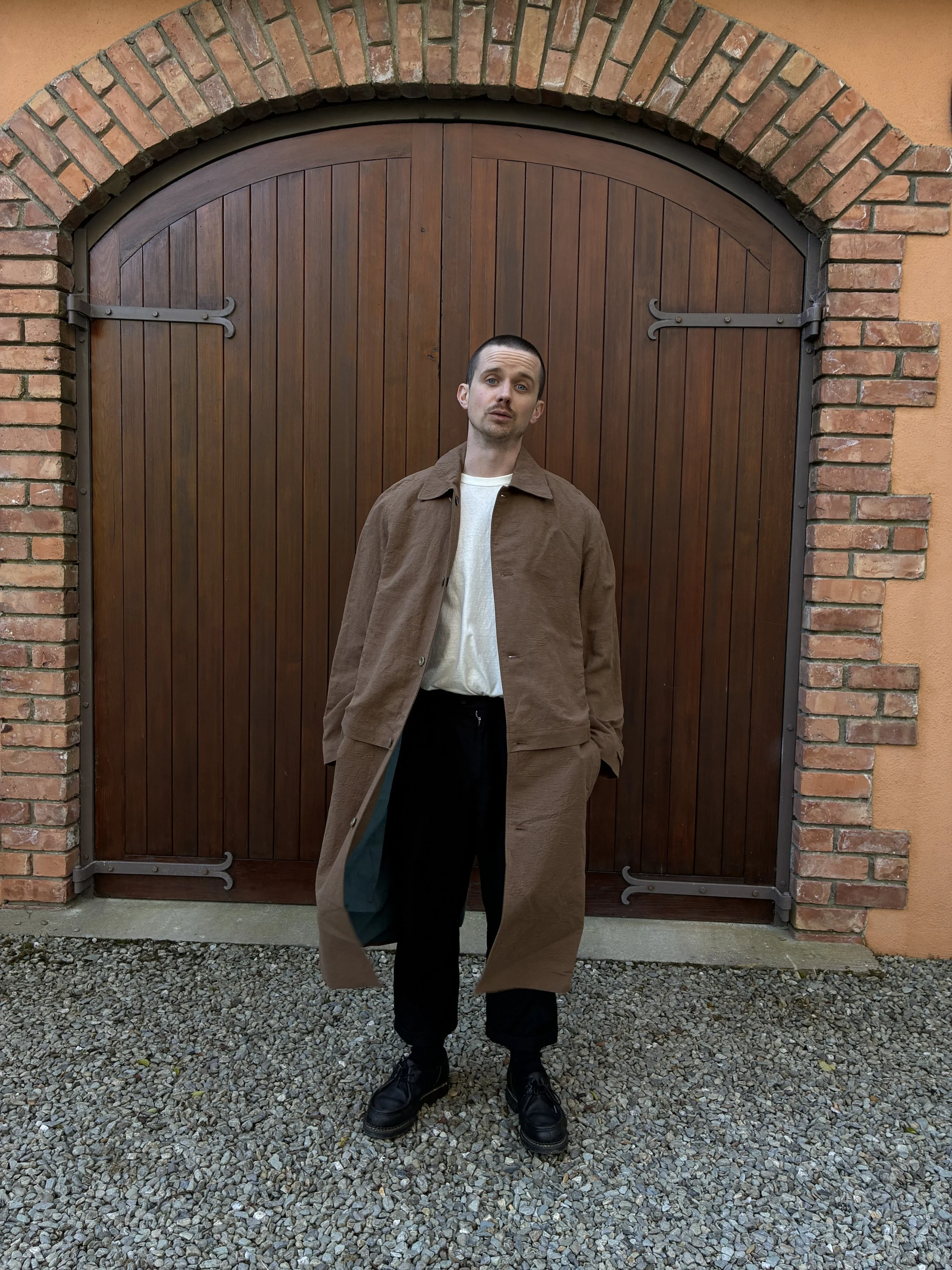 Man in front of door wearing Frank Leder Reversible Coat in Brown and Teal