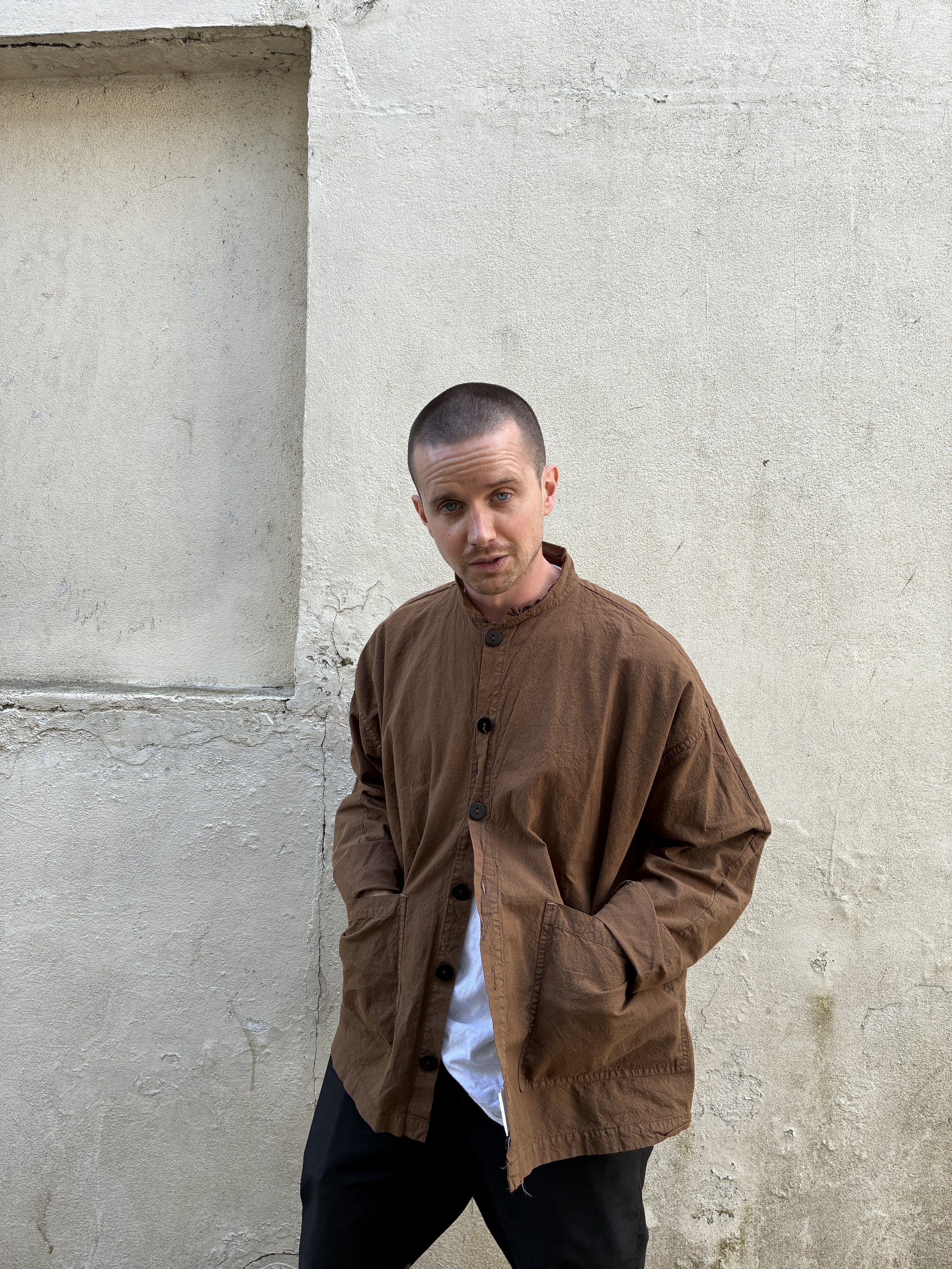 Man in front of wall wearing Tender Co Type 485 Isosceles Brown Hat Shirt
