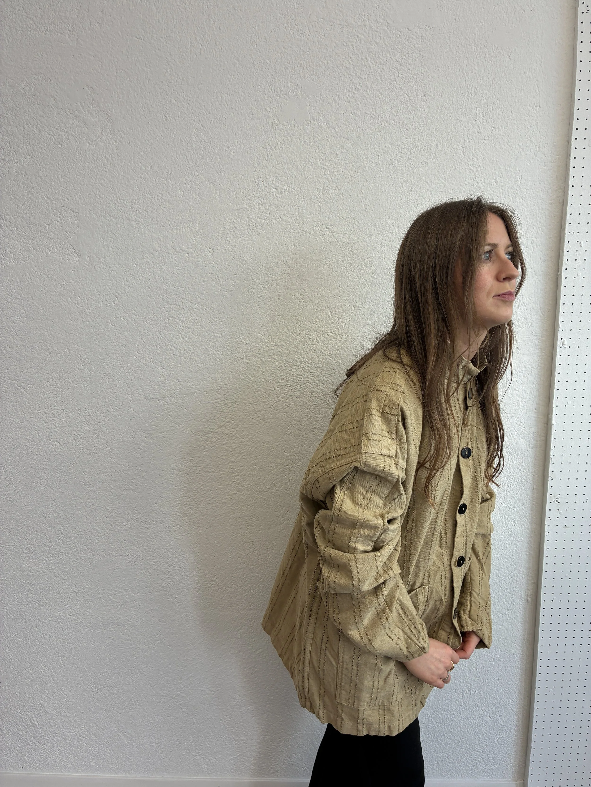 Woman buttoning up Drab Weld Tender Co Type 485 Isosceles Shirt in front of white wall