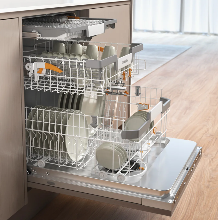 Open Miele dishwasher with fully loaded racks, showcasing durable design and spacious interior for modern kitchens.