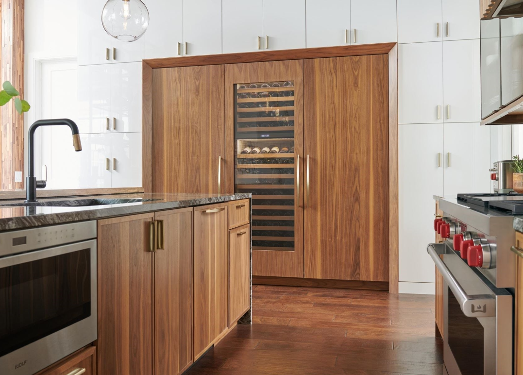 Luxury kitchen with custom wood cabinetry featuring a built-in Sub-Zero wine fridge, Wolf range, and modern finishes.