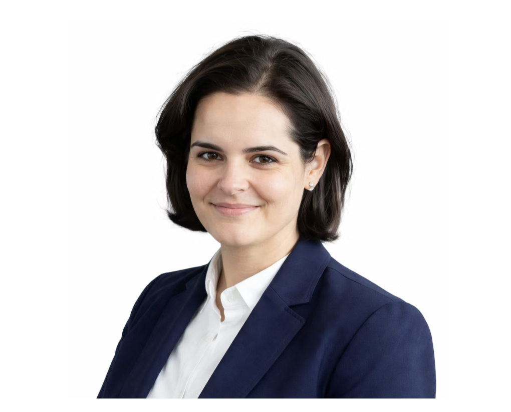 A woman with short dark hair wearing a navy blazer and white shirt, smiling against a white background.