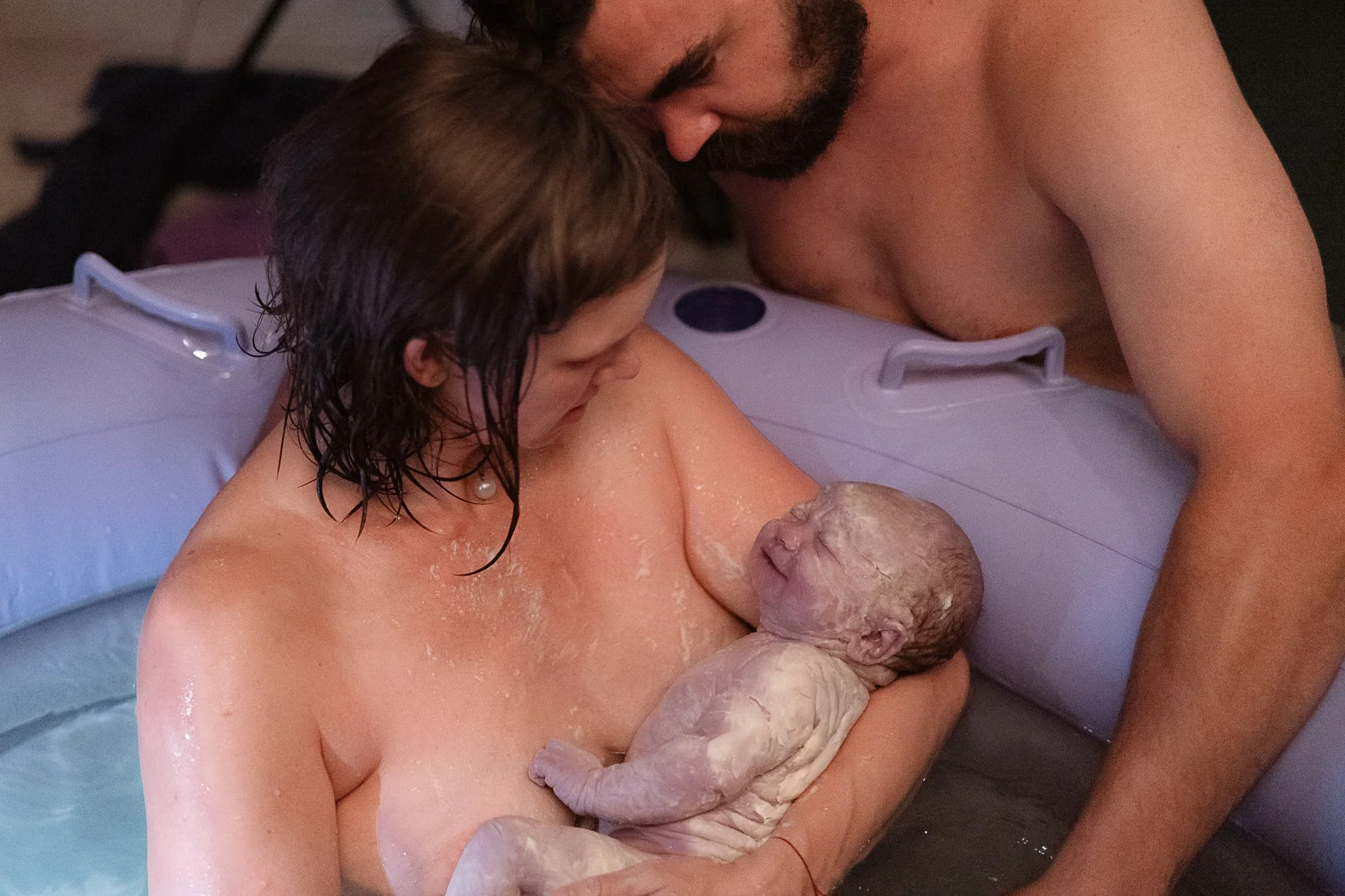 birth photograph, mother father holding freshly born baby in birth pool birth photography golden bc