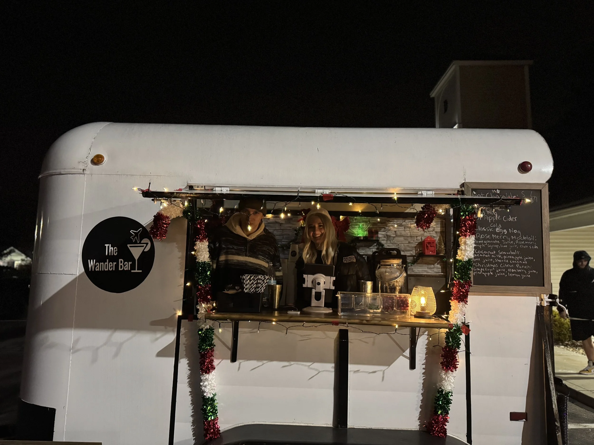 Male and female event bartenders smile inside of bar trailer while serving beverages at a Christmas party in Londonderry New Hampshire