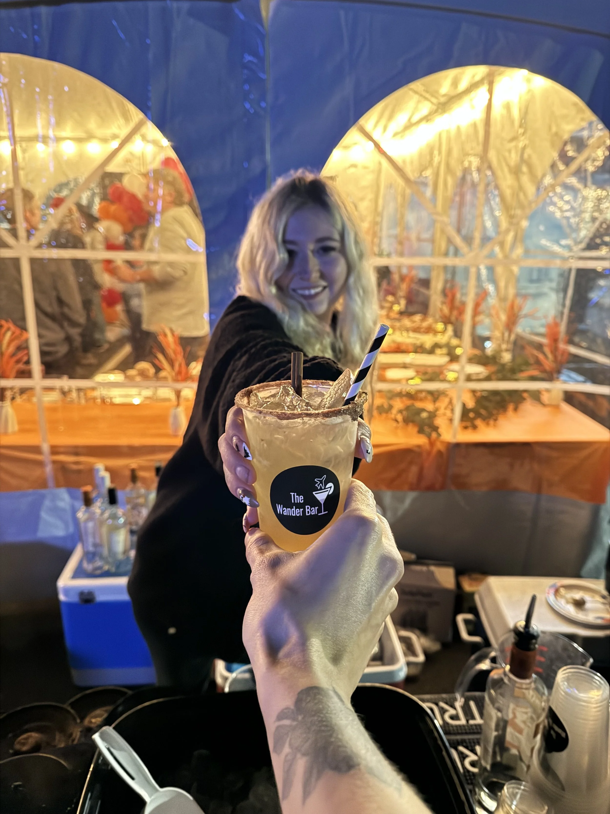 Smiling female event bartender handing a custom cocktail to a customer at a company event in Hampstead New Hampshire