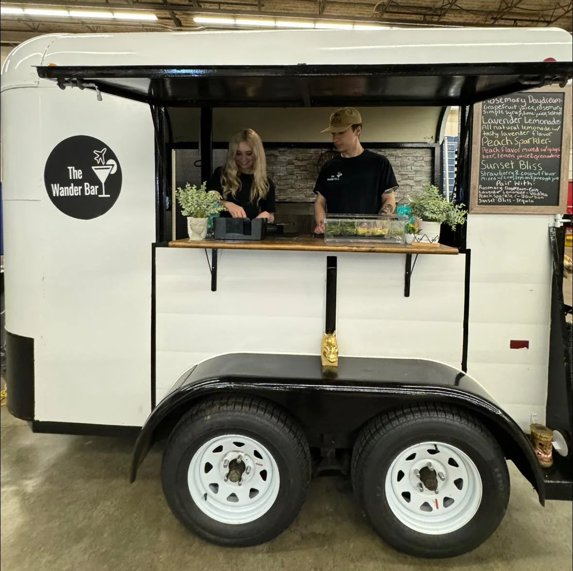 Male bartender watches as female bartender prepares a mocktail inside of a horse bar trailer at a wedding in Wilmington Massachusettsshow event