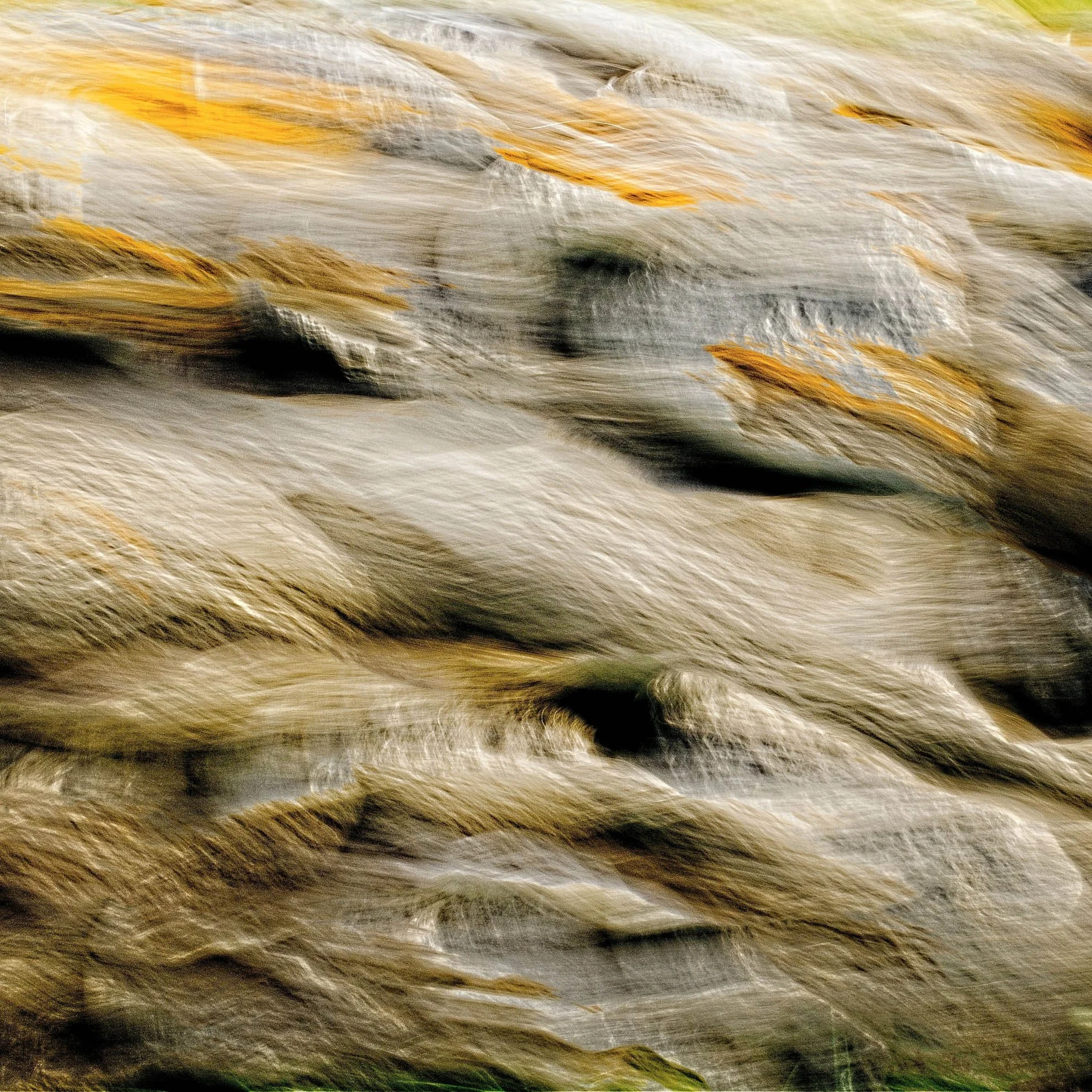 Close-up of a rushing stream with water flowing rapidly over rocks and stones.