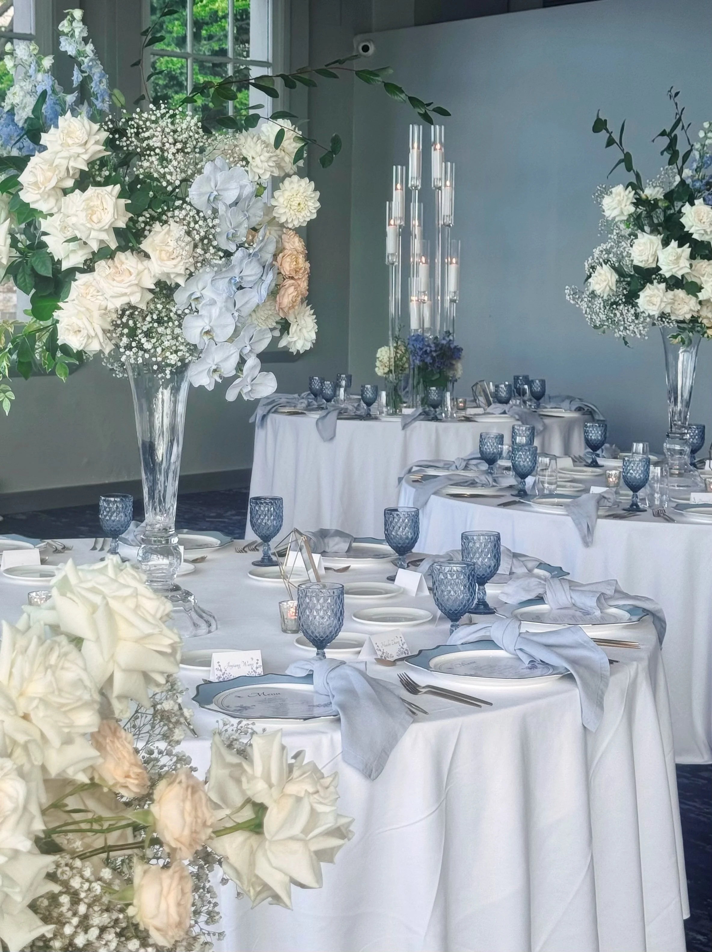 In a larger room, scale matters. A taller, more generous centrepiece can help the styling hold its presence within the space，always balanced against the overall vision of the wedding.

Our role is to guide that scale carefully, so the design feels im