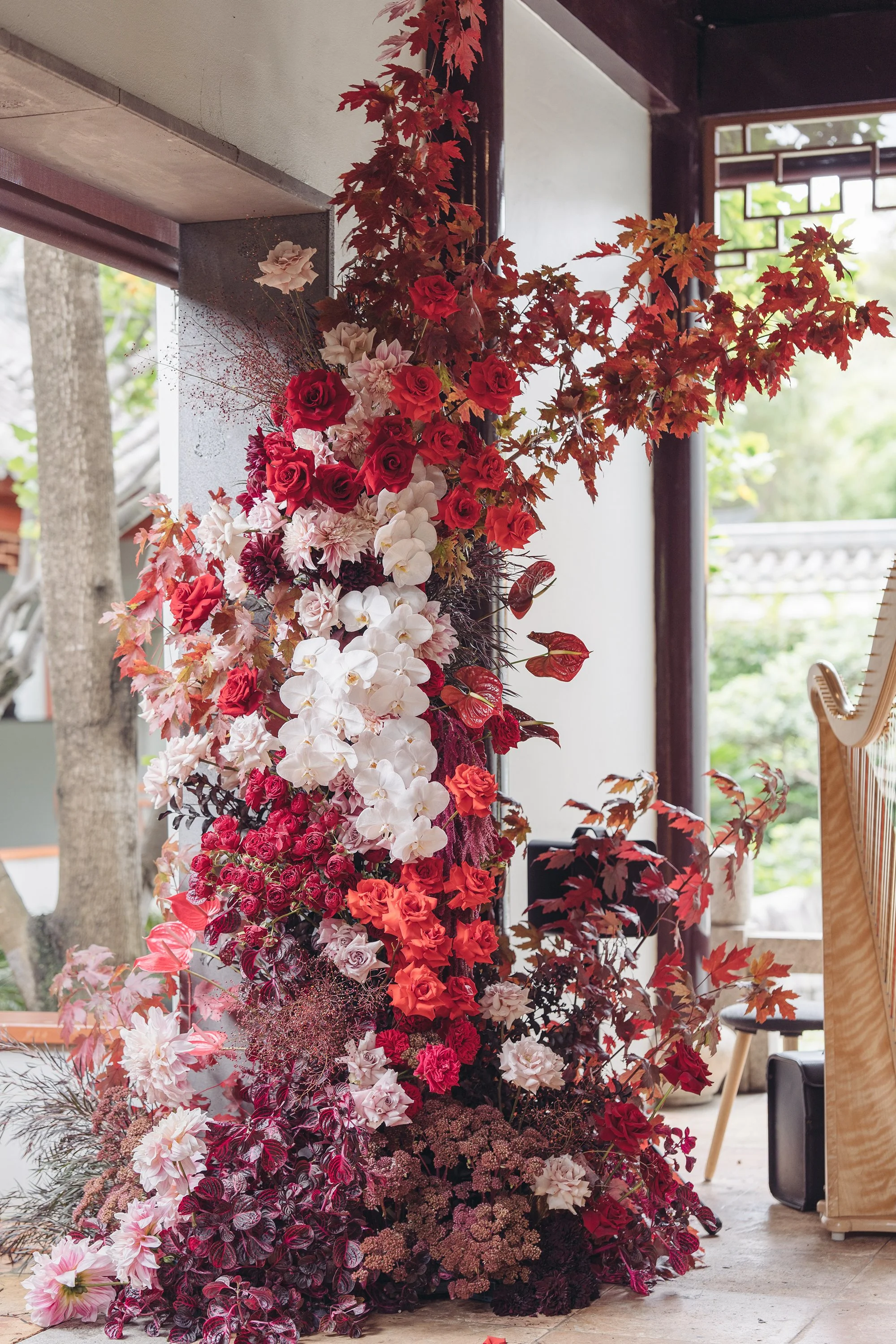 Floral arrangement with red, white, and orange flowers, including roses and orchids, and autumn leaves.