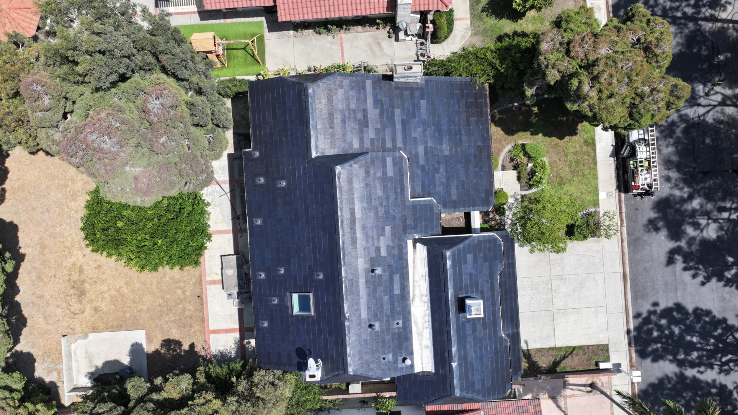 Aerial drone photo showcasing a Tesla solar roof freshly cleaned by Guru Solar Cleaning in Long Beach, California. This rooftop system was maintained using purified water and soft-brush equipment to protect the solar tiles while removing dust, salt,
