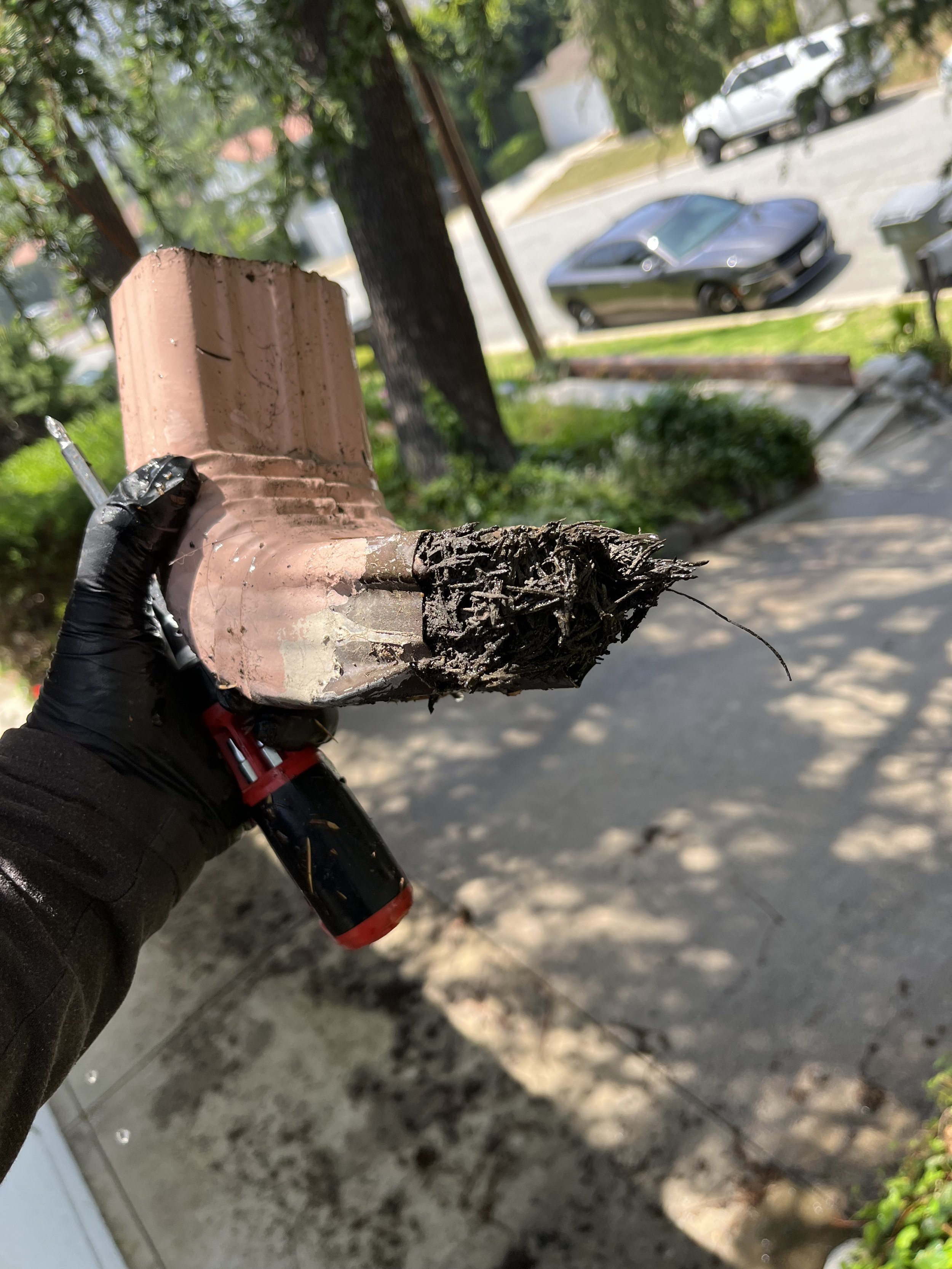 This photo captures the removal of compacted debris from a severely clogged gutter elbow during a full gutter cleaning service in Glendale, CA. Guru Solar Cleaning provides thorough and professional gutter maintenance to ensure proper drainage, preve
