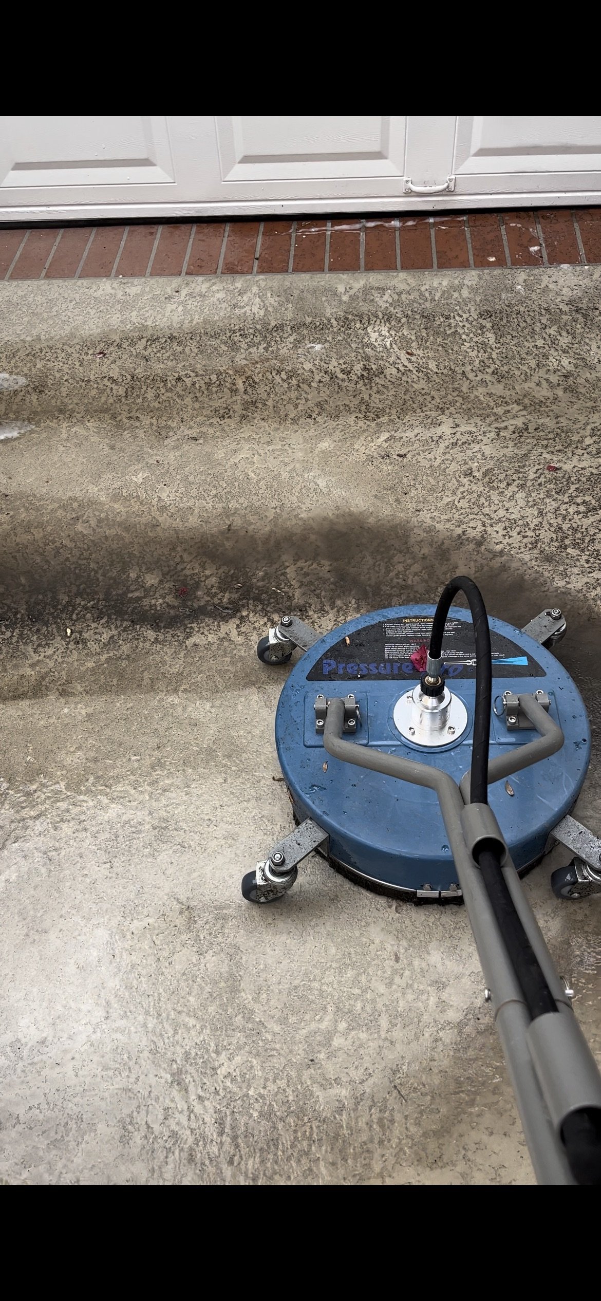 Professional pressure washing in Long Beach, California, targeting a driveway heavily affected by organic growth such as moss, algae, and dirt buildup. Guru Solar Cleaning used high-pressure surface cleaning equipment to restore the driveway’s appear