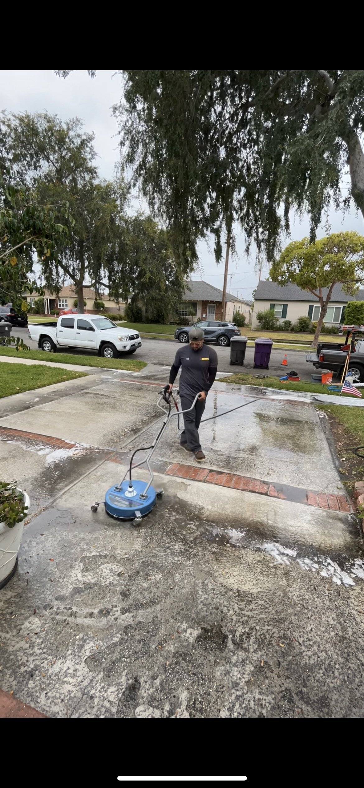 Professional pressure washing service in Long Beach, California, using a commercial-grade surface cleaner to remove algae, moss, and organic growth from a residential driveway. This method ensures even, deep cleaning without damaging the concrete, re