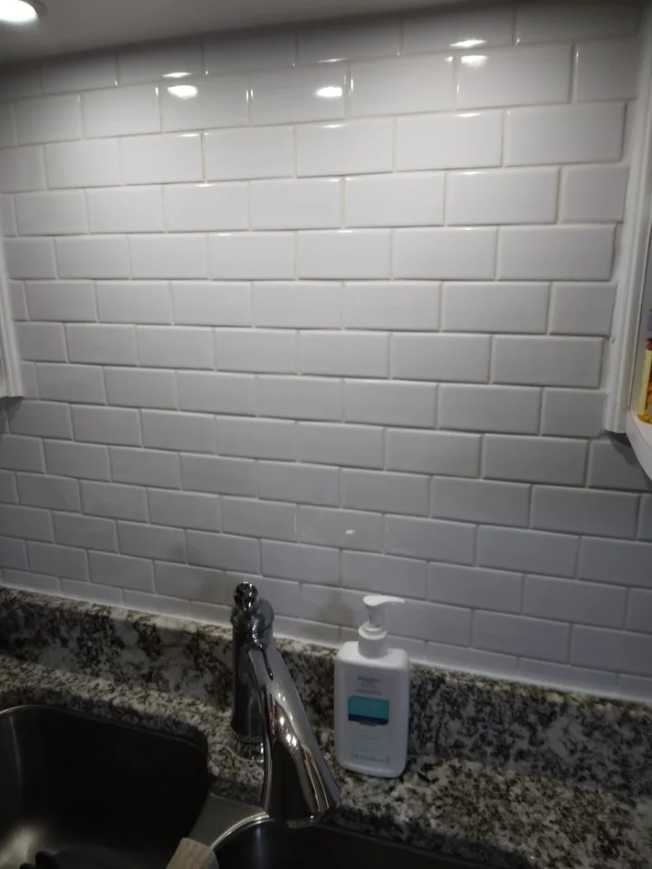 Kitchen backsplash with white subway tiles, granite countertop, and a silver faucet with a bottle of hand soap.