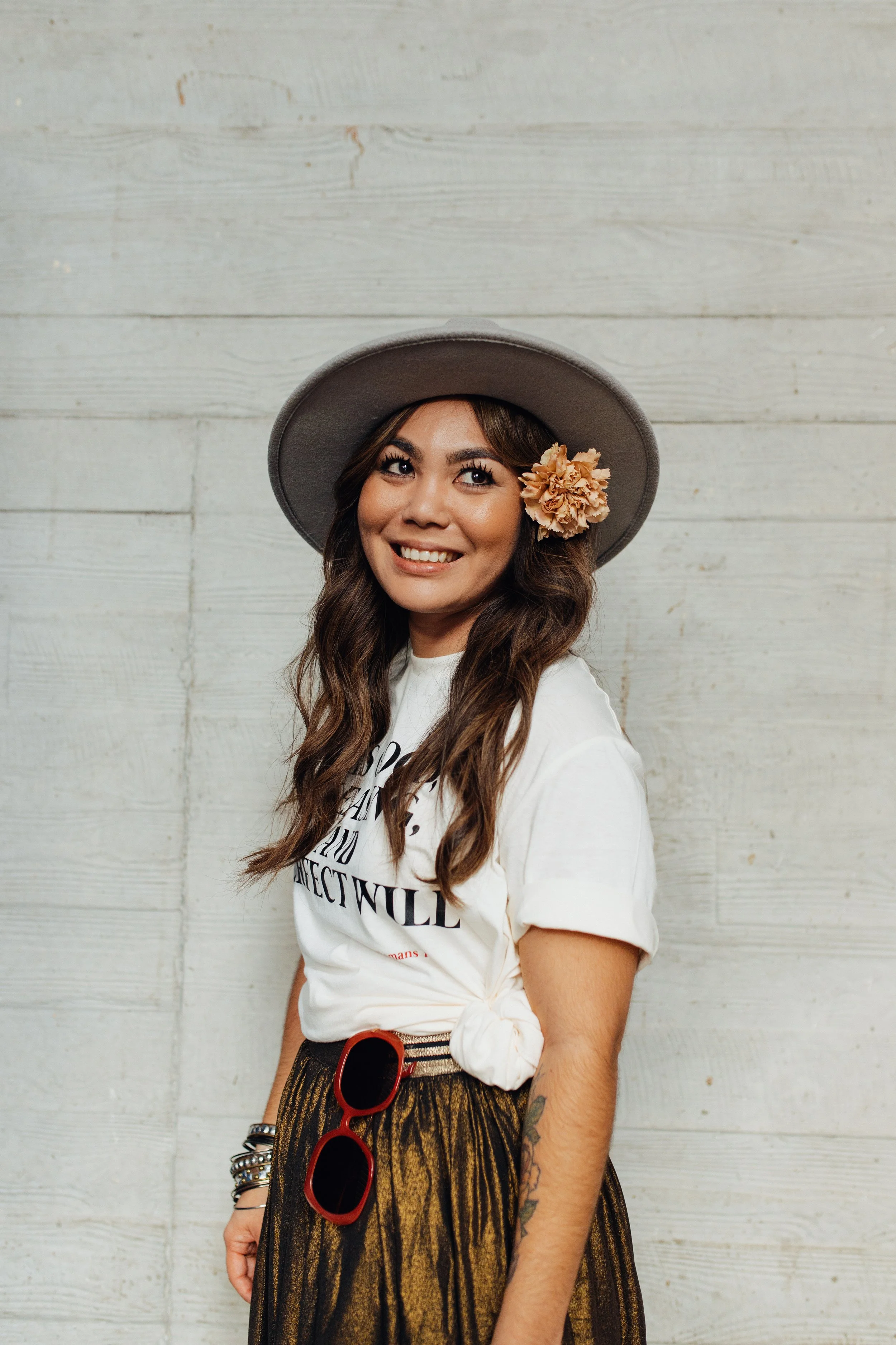 Niki of Sustainery Hair Studio and Niki Ann Tan Hair standing in front of a white wall smiling