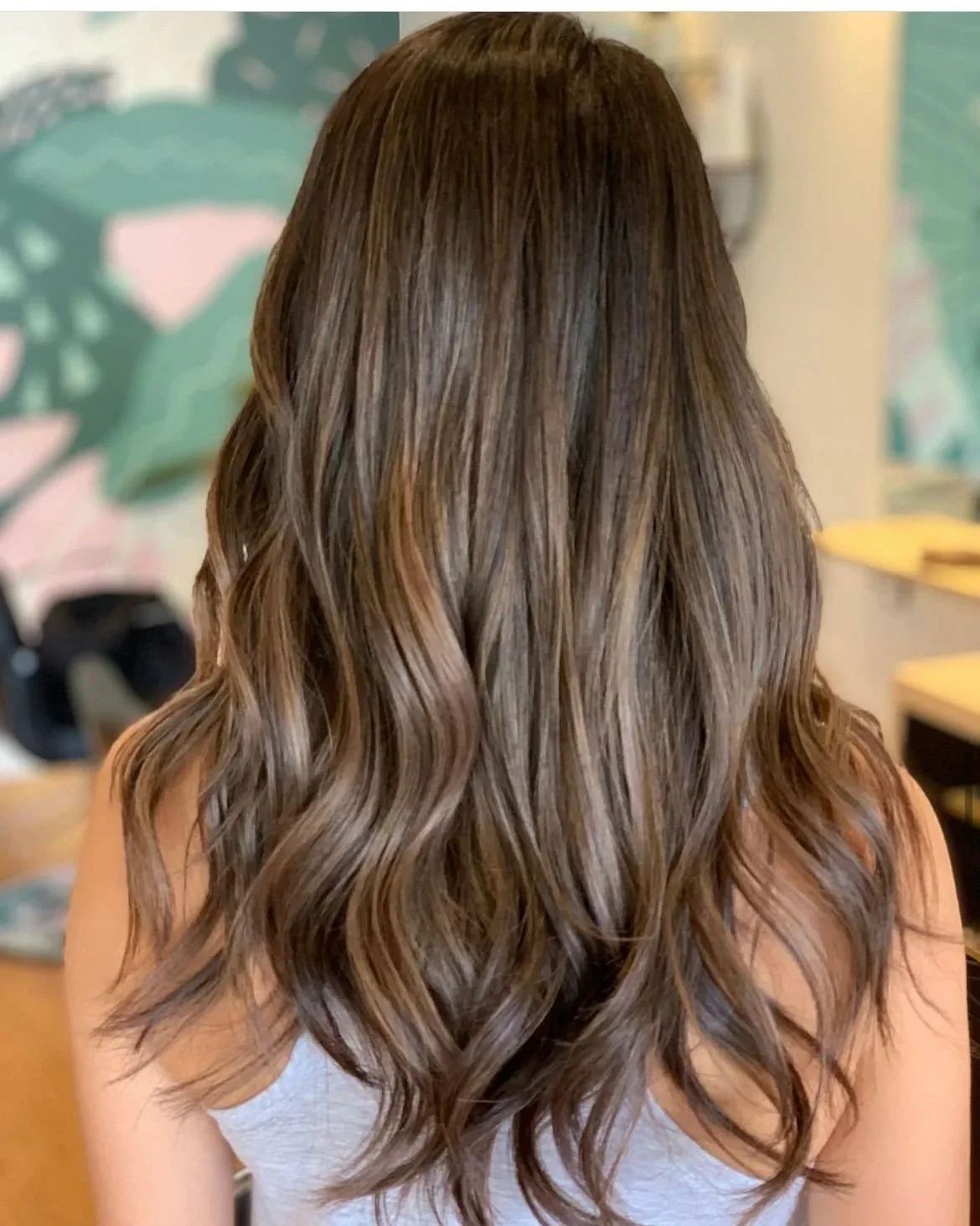 Dimensional brunette hair color with soft waves at Sustainery Hair Studio