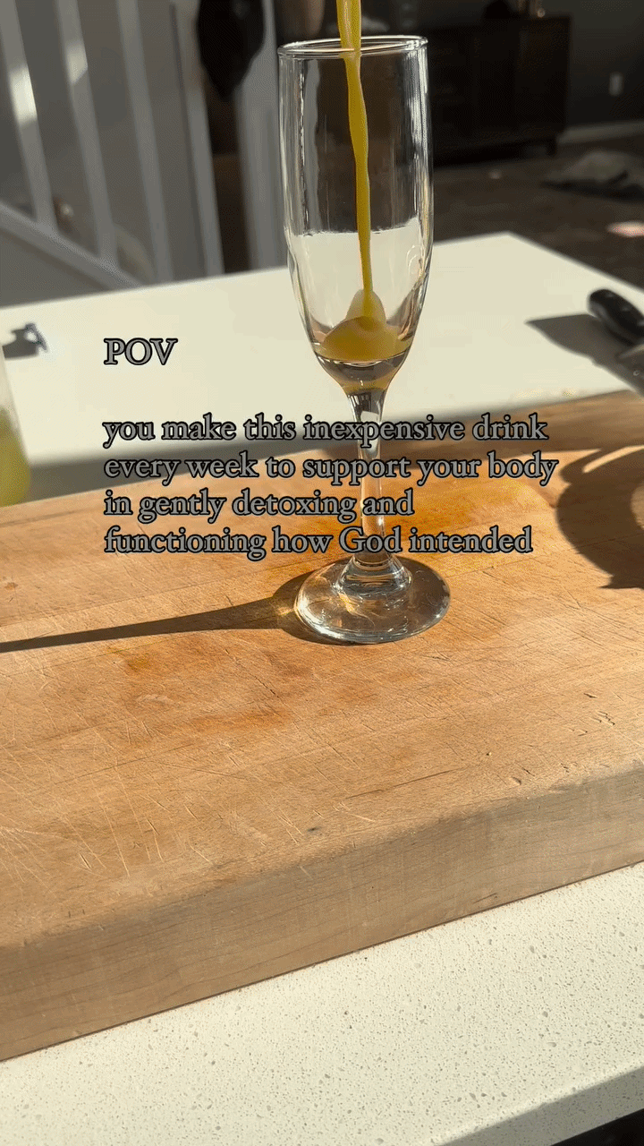 Whole lemons and ginger root resting on a wooden cutting board next to a kitchen sink, with video text overlay reading "POV you make this inexpensive drink every week to support your body in gently detoxing and functioning how God intended".