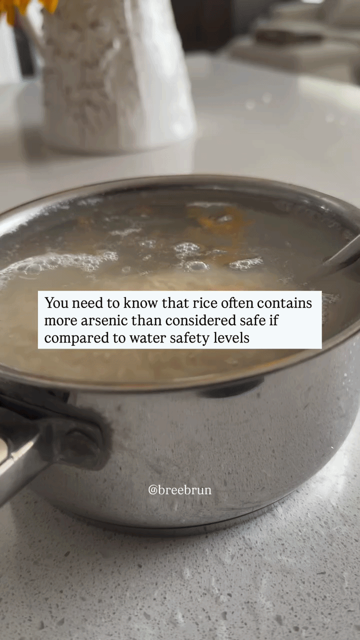 A person rinsing cooked rice in a fine mesh strainer under running water over a kitchen sink to remove arsenic.