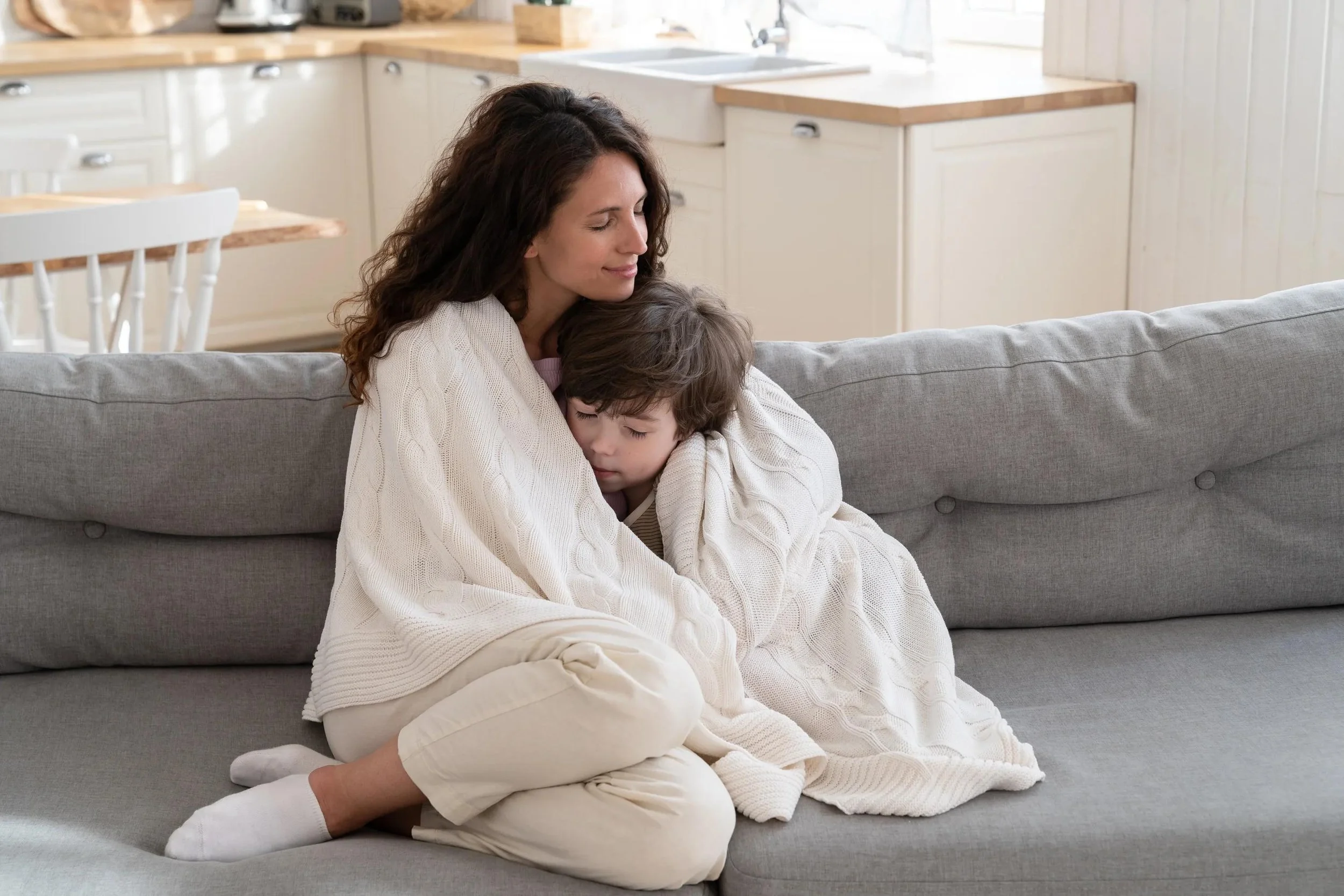 A mother comforting a child wrapped in a blanket.