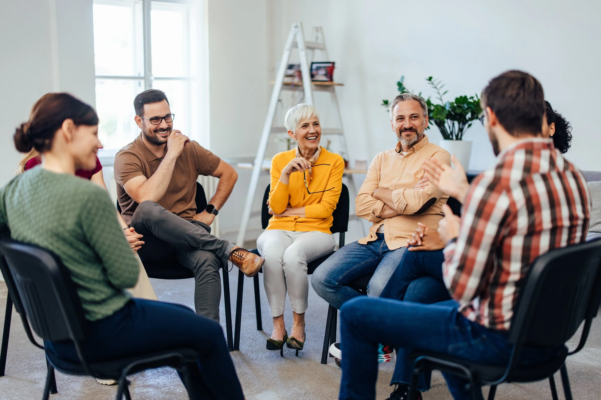 A diverse group of people gather for a facilitated mindfulness and creative experience for group wellness during a staff retreat.