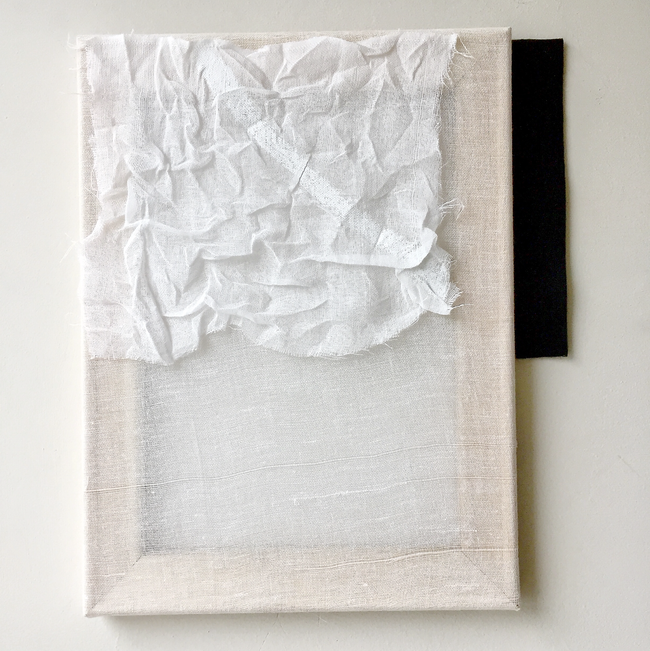 Textured abstract artwork with crumpled white fabric layered over a light surface with a black backing