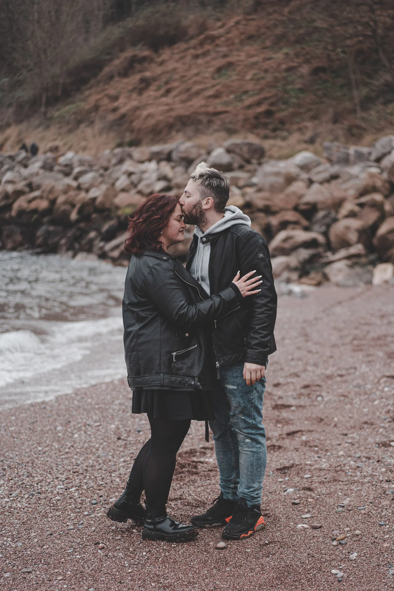 Man kissing his girlfriends forehead on a beach in Cornwall