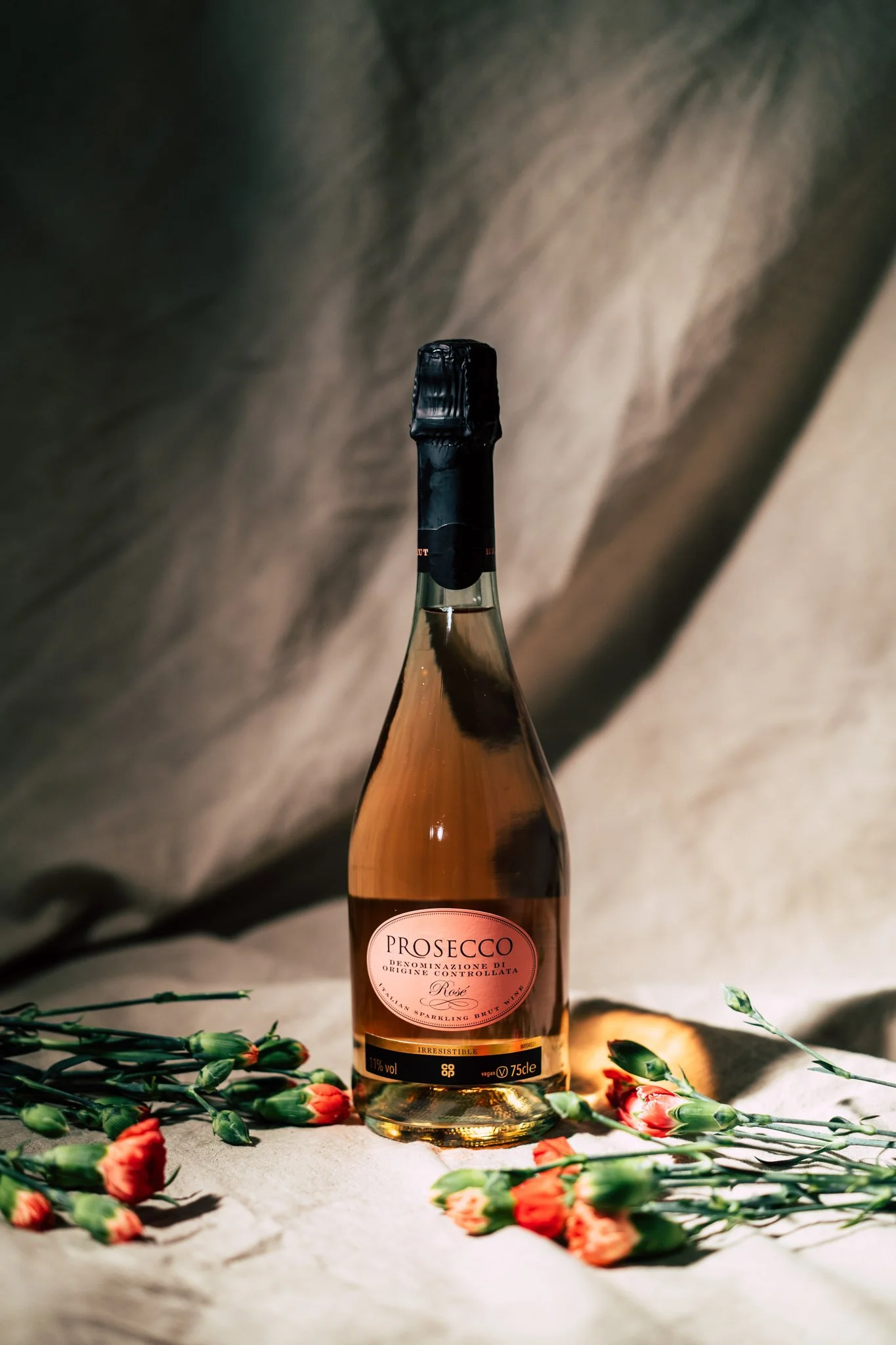 Studio product photography of a prosecco bottle surrounded by flowers in Coventry, West Midlands