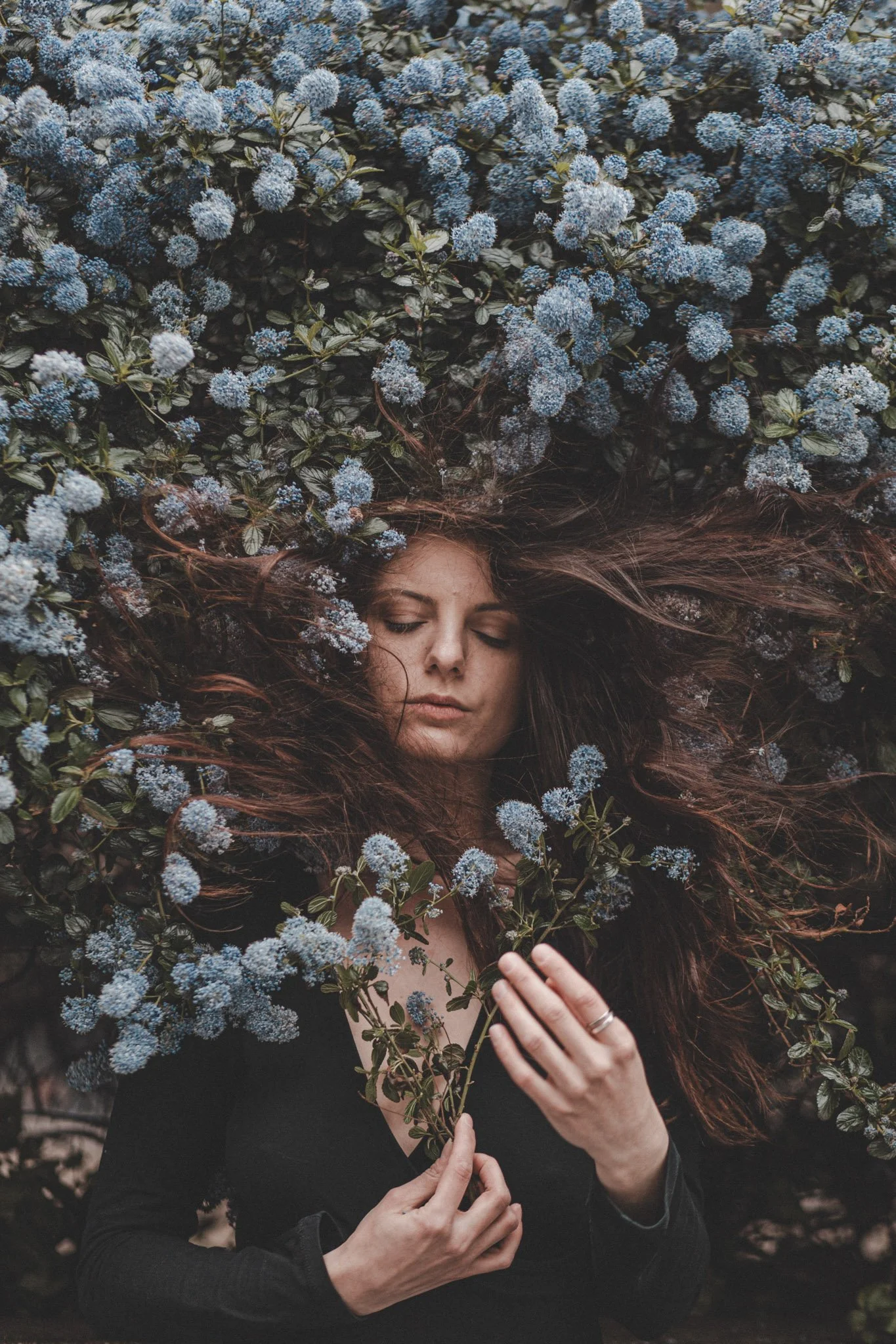 Girl between blue flowers with eyes closed