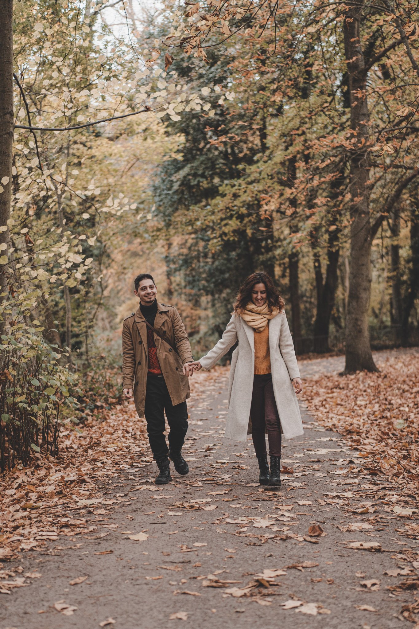 Young engaged couple holding hands and smiling at their save the date photoshoot in Coombe Abbey Park, Coventry