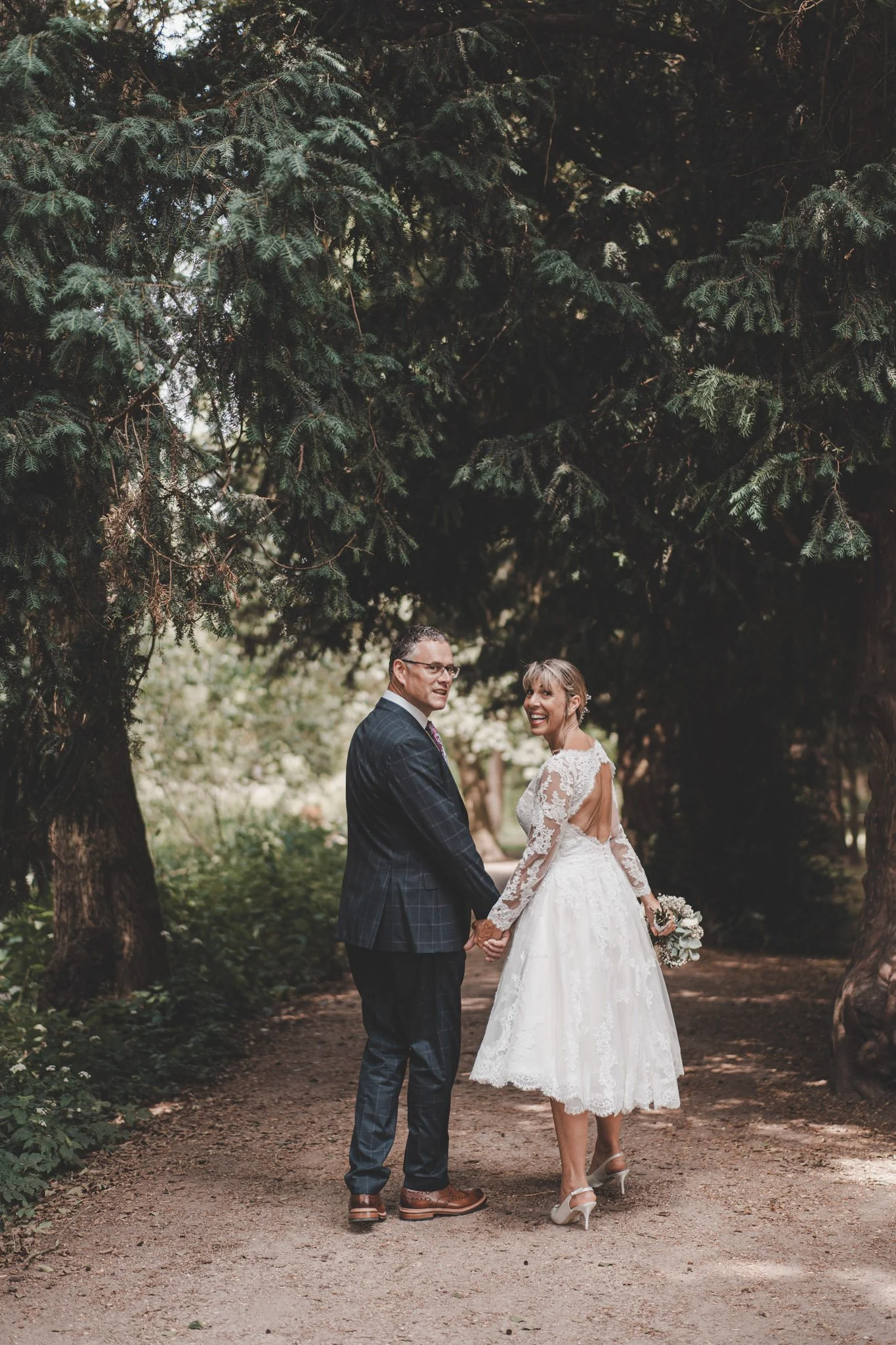 Newly weds photographed from the back while walking and looking at the camera