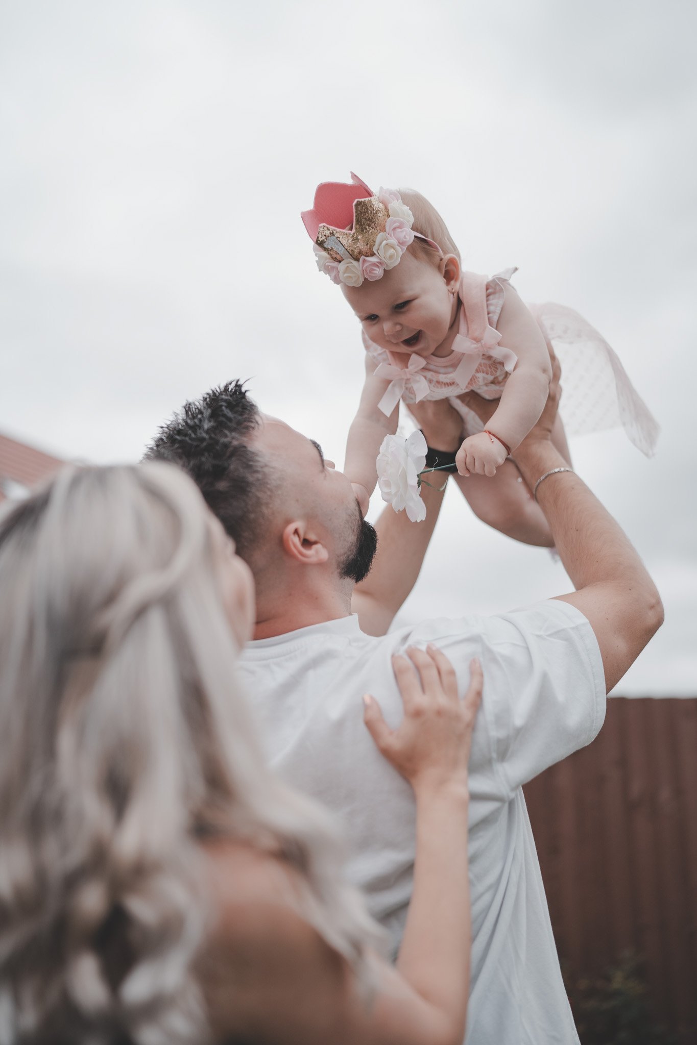 Parents playing with their little daughter, wearing a crown and pink dress at a birthday party in Coventry