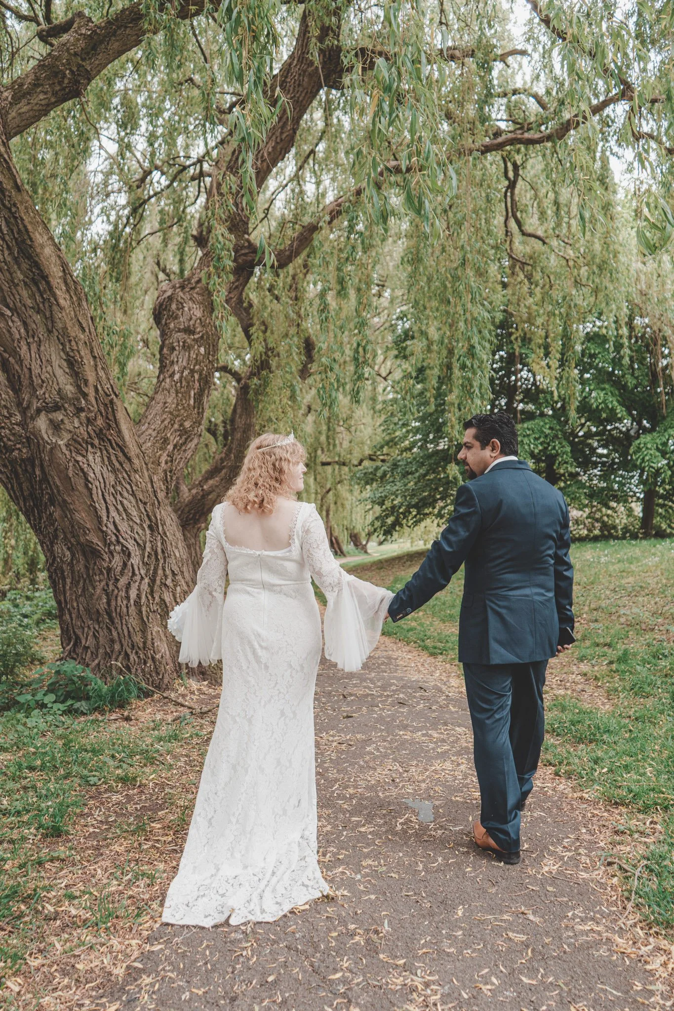 Bride and groom photographed in a park in Coventry while holding hands