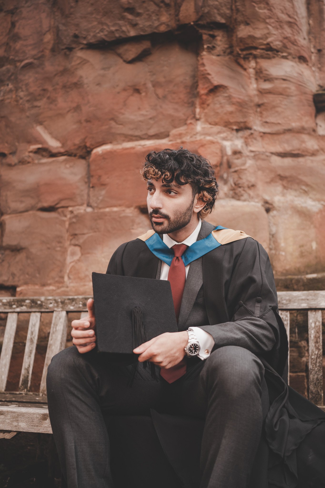 Boy sitting on a bench in Coventry cathedral ruins during a graduation photography session