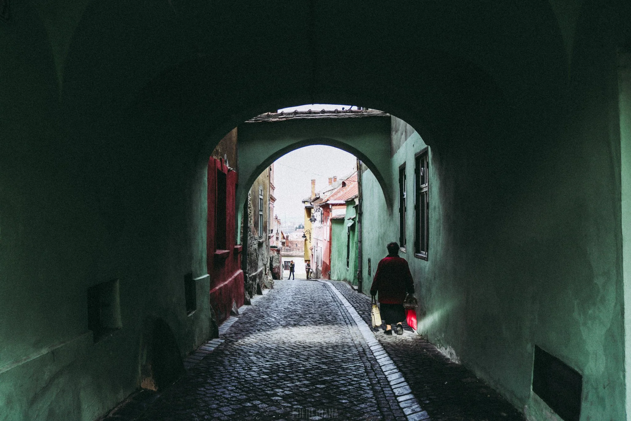 Photo of an old woman walking on a old street in Sibiu, Romania
