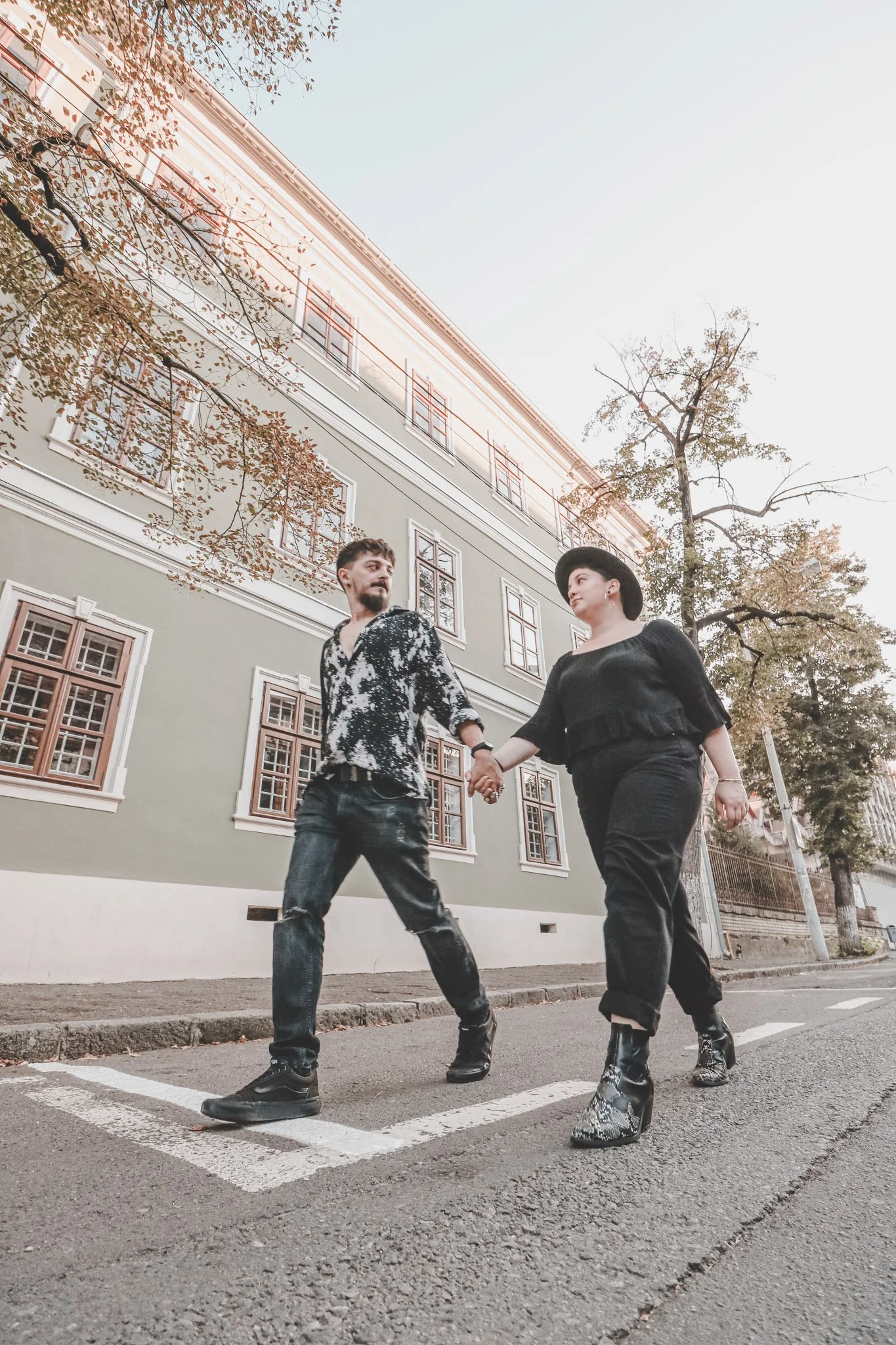 Young couple photographed holding hands walking on a street in Cluj-Napoca, Romania