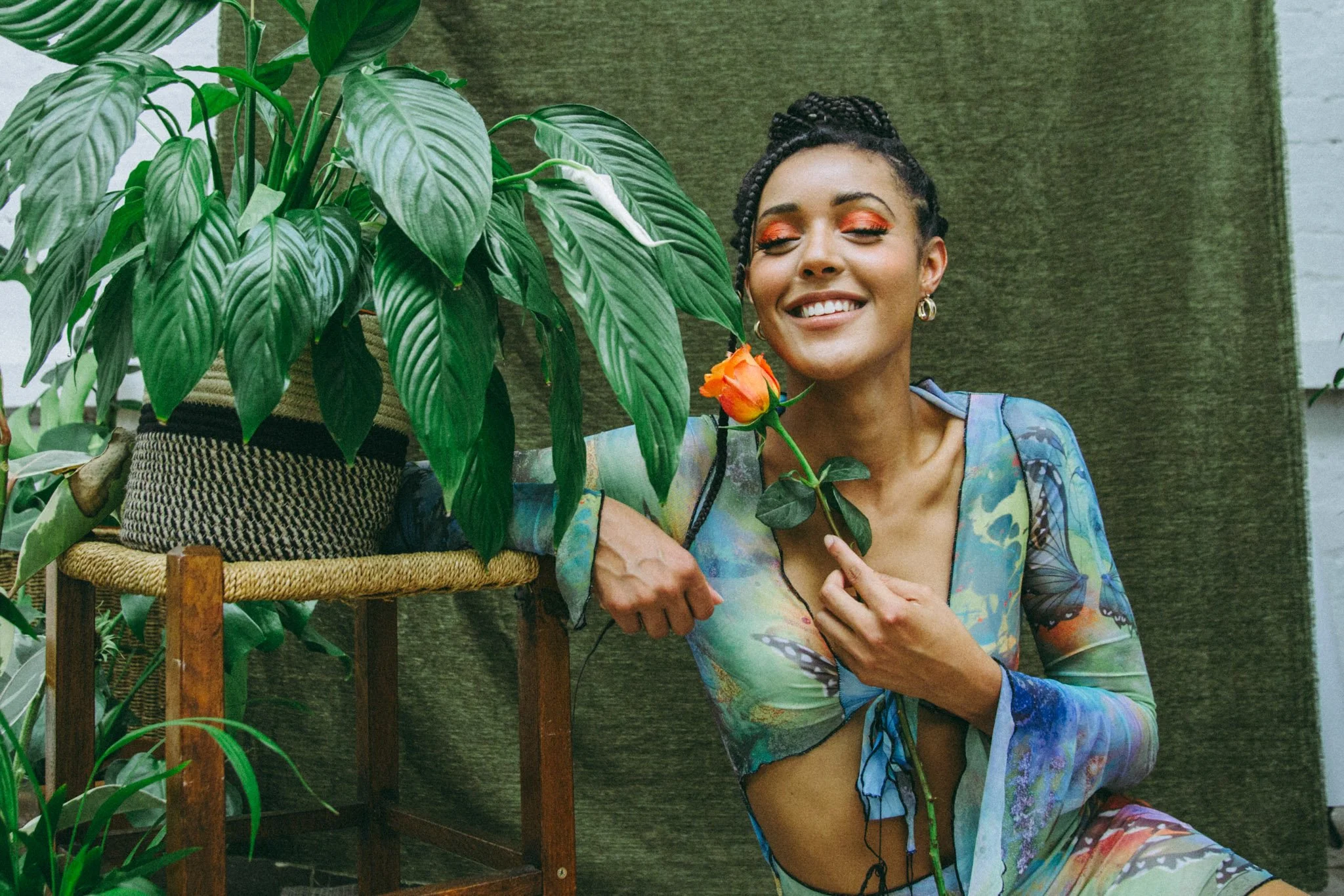 Singer Danniella Dee holding a rose in a studio photoshoot with a green background