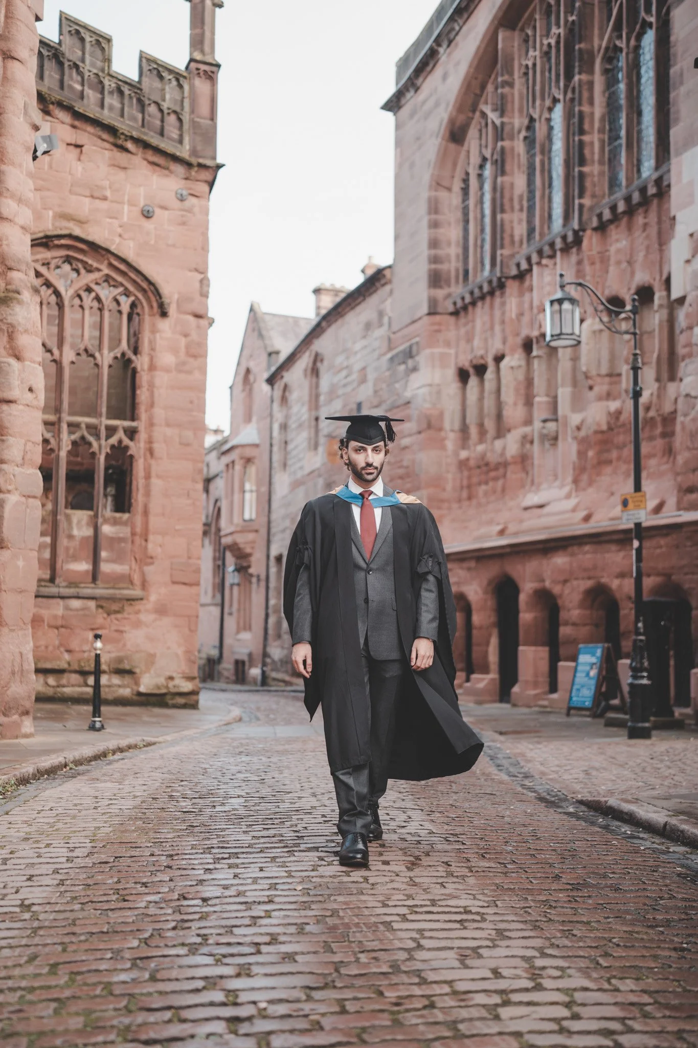 Boy wearing graduation clothes walking through Coventry centre