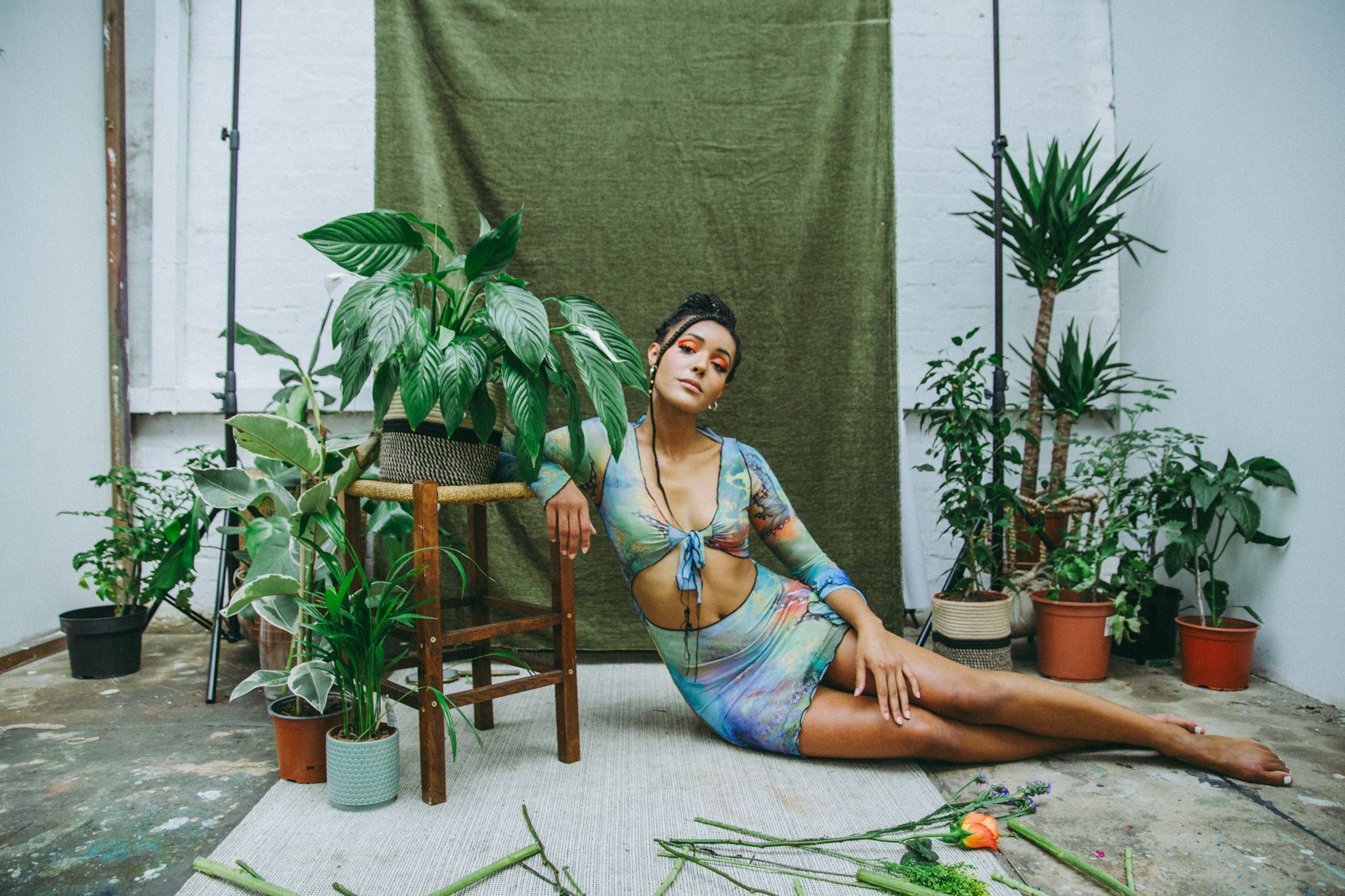 Full body photo of London musician, Danniella Dee, surrounded by plants in a studio in Birmingham