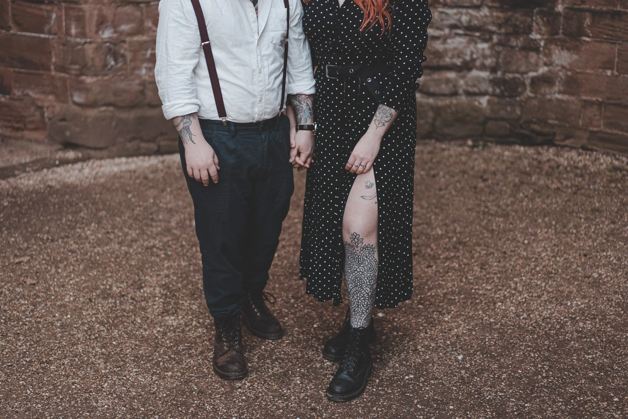 Detail of leg tattoos while couple is holding hands