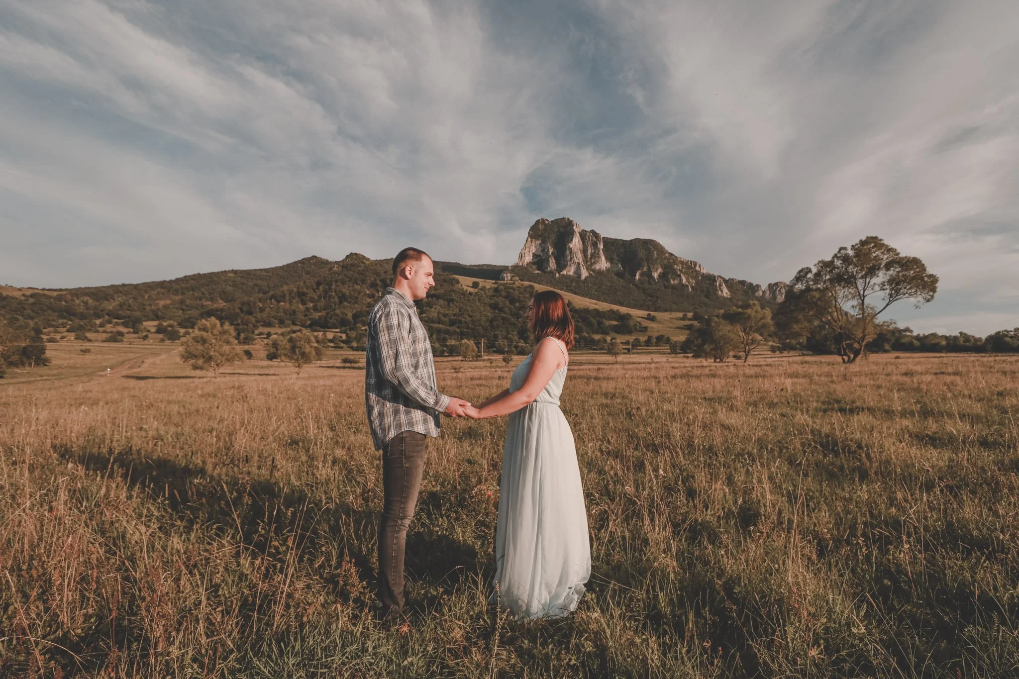Landscape photo of a couple holding hands and looking at each other in Rimetea, Romania