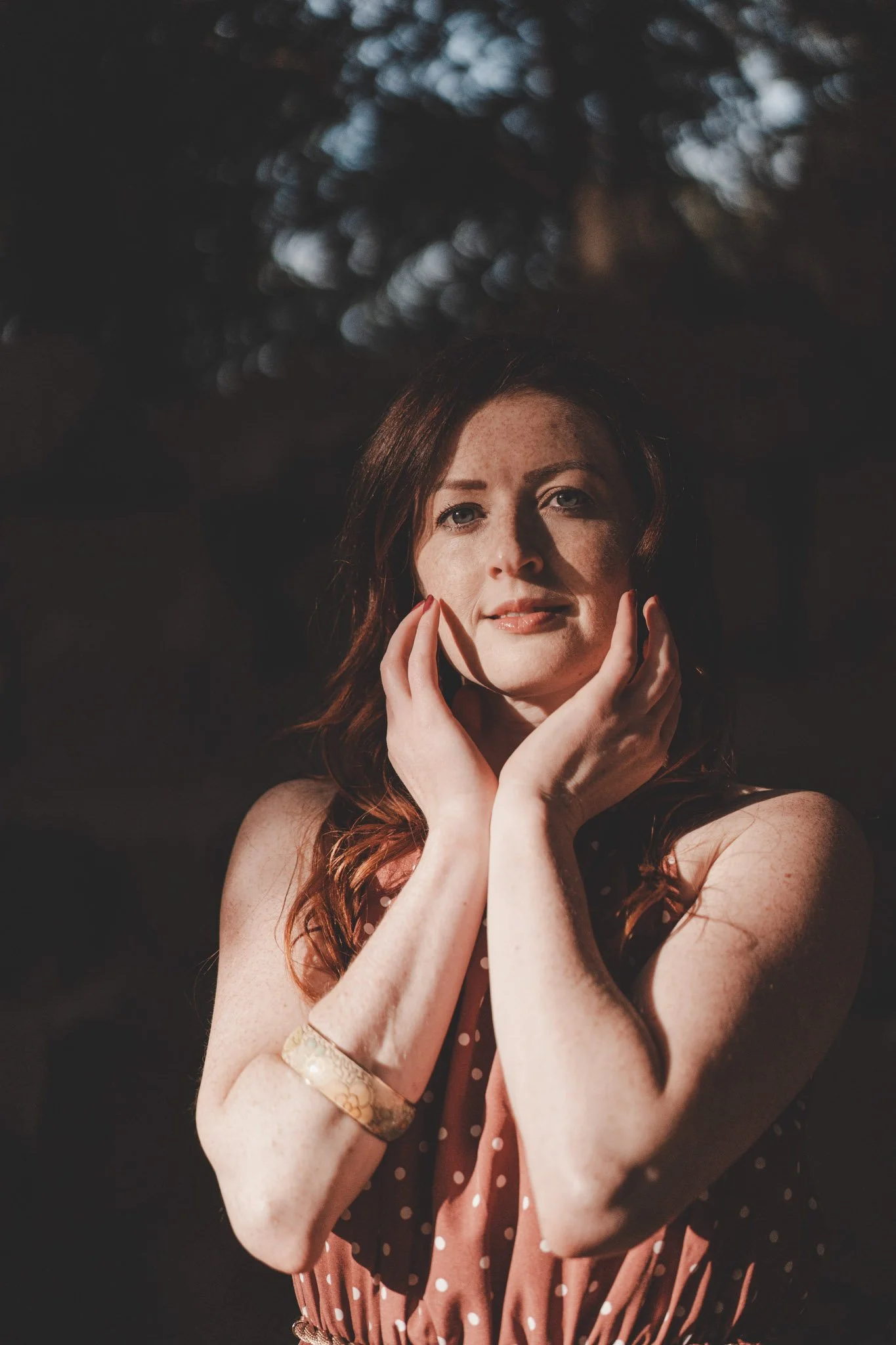 Moody outdoor portrait of a woman with her hands on her face