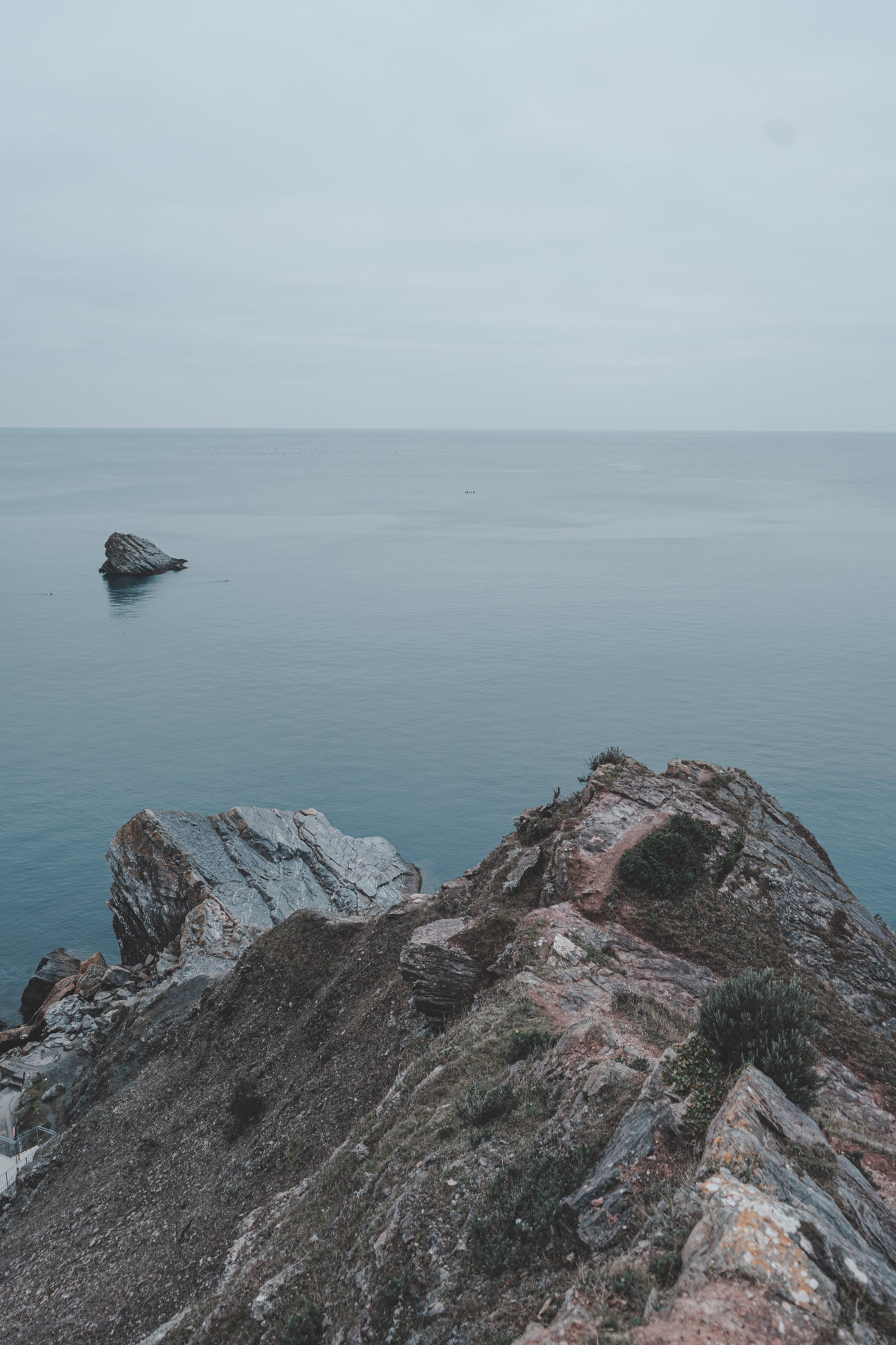 Vertical landscape image of rocks and sea from Torquay, Cornwall