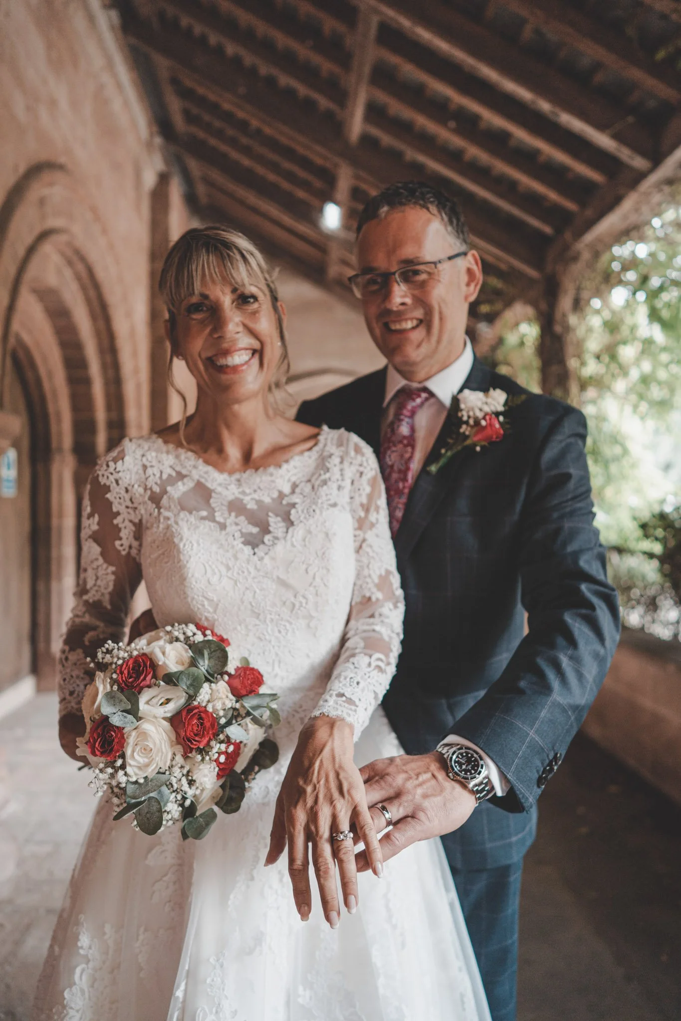 Photo of bride and groom showing their wedding rings at the camera at Coombe Abbey Hotel, Coventry