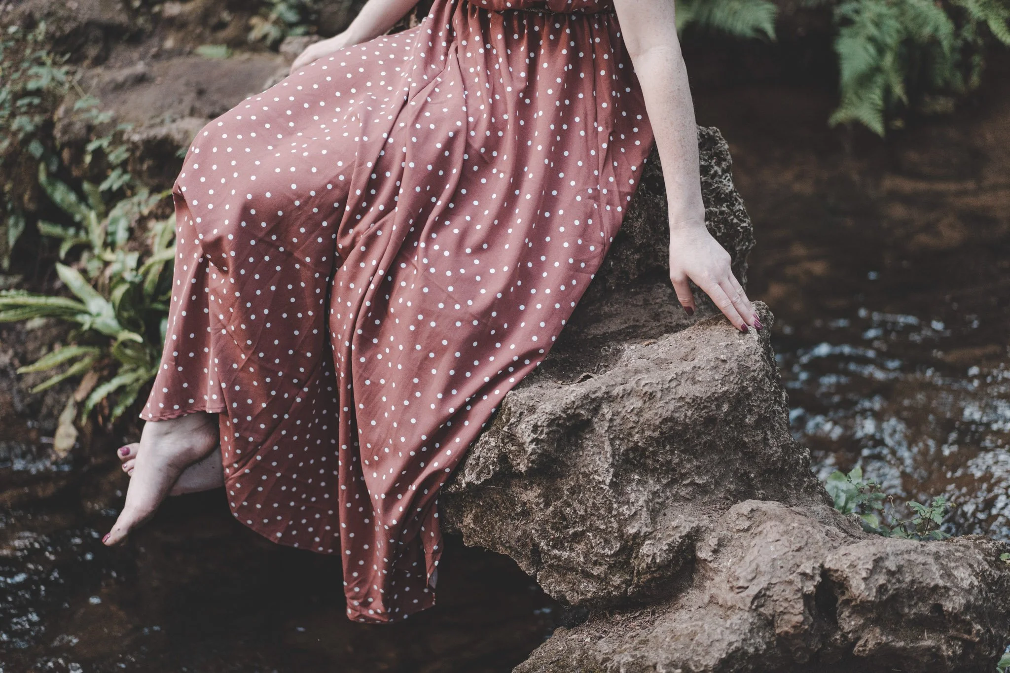 Details of a barefoot girl wearing a red dress with white dots