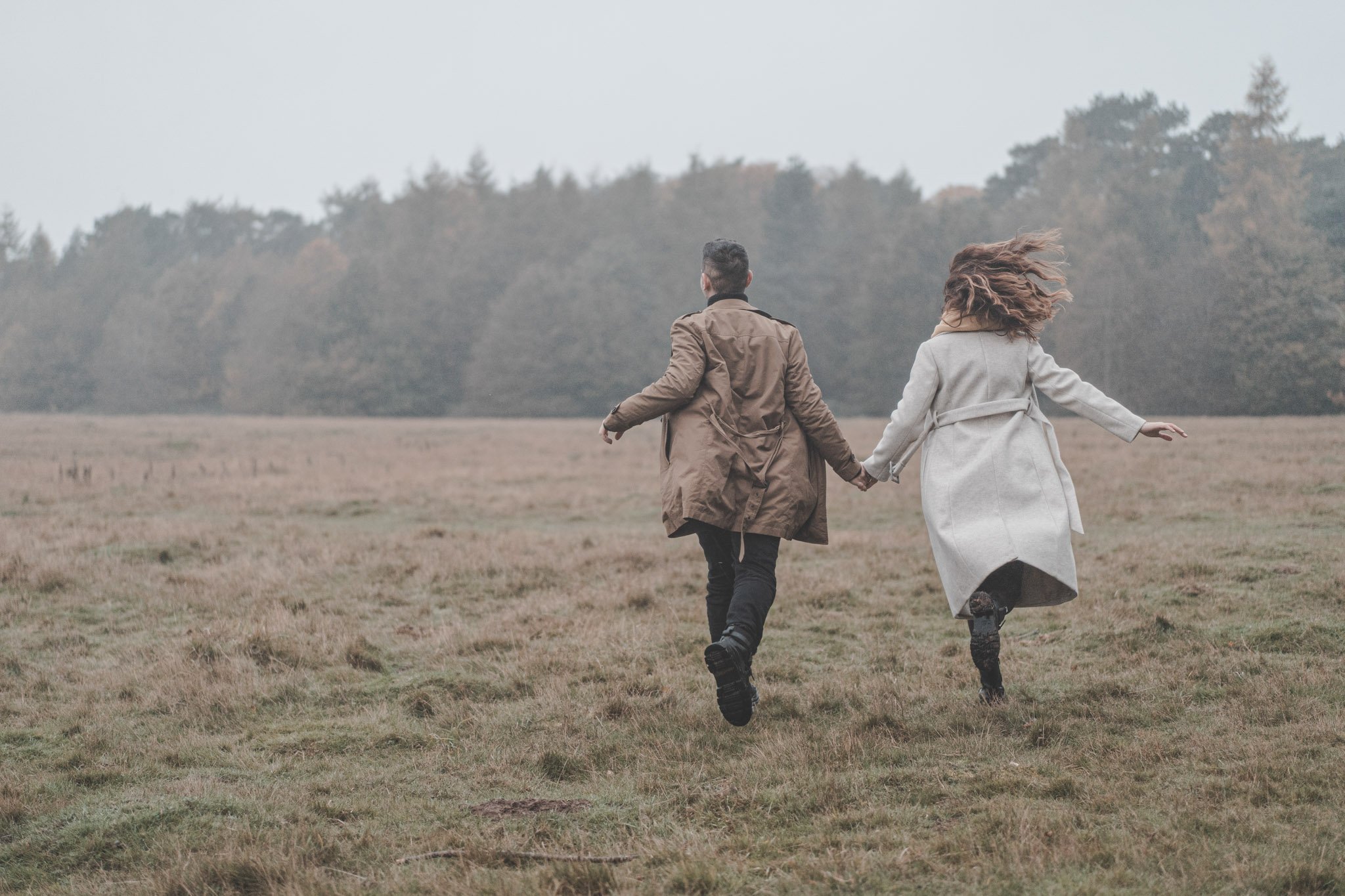 Engaged couple running and holding hands at Coombe Abbey Park, Coventry