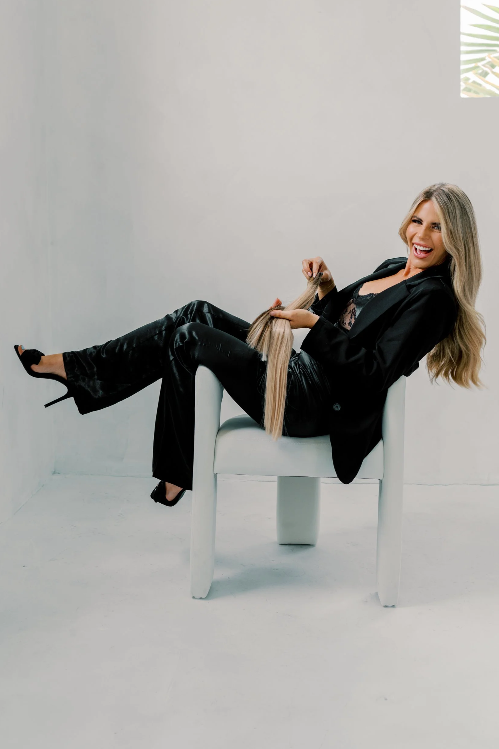 A white liquid soap dispenser with a black pump on a brown fabric surface against a plain white wall.